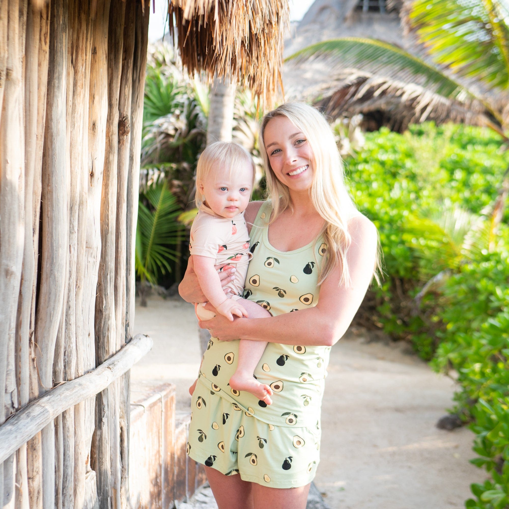 Mom holding child wearing Kyte Baby Shortall in Peach