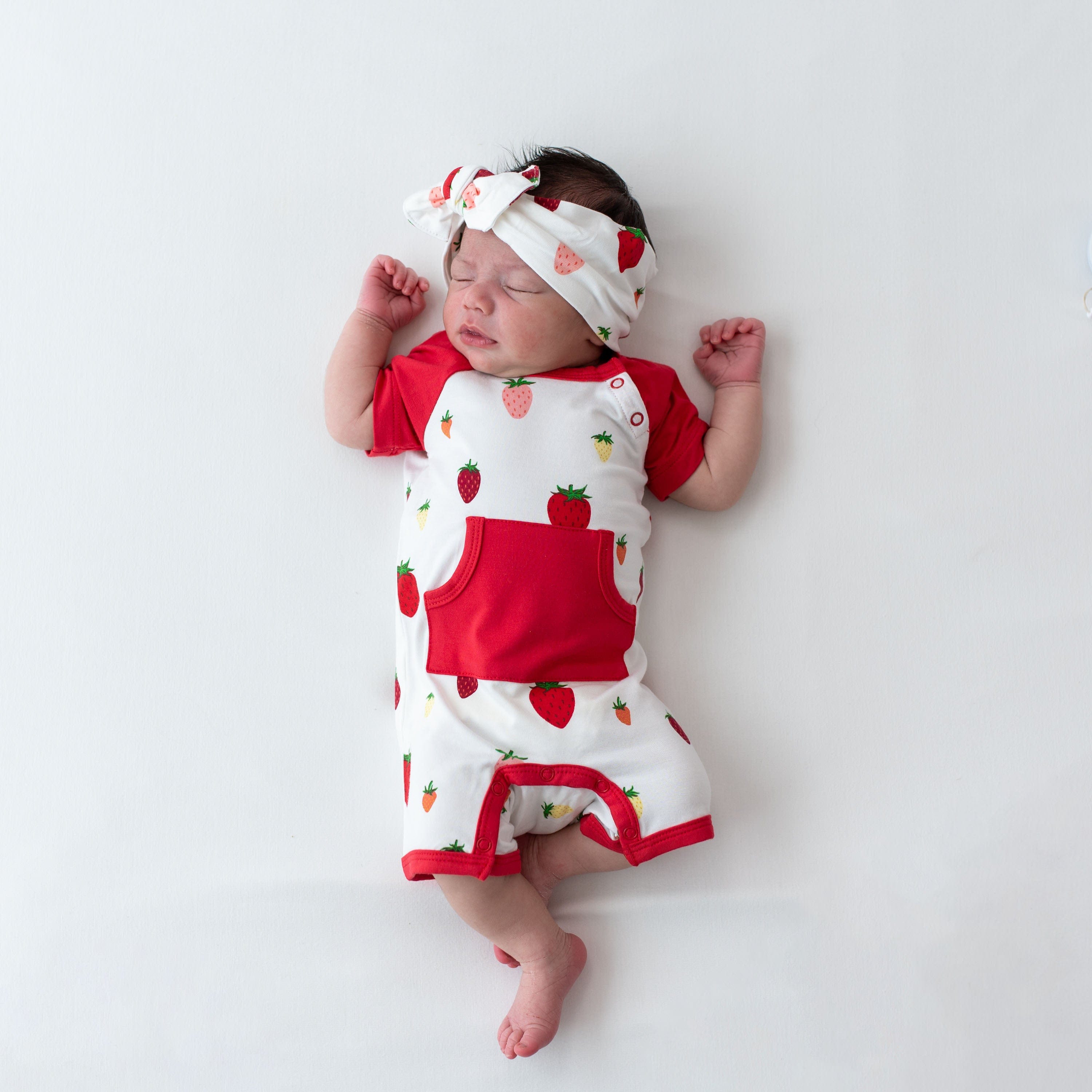 Newborn wearing Kyte Baby bamboo Shortall in Strawberry