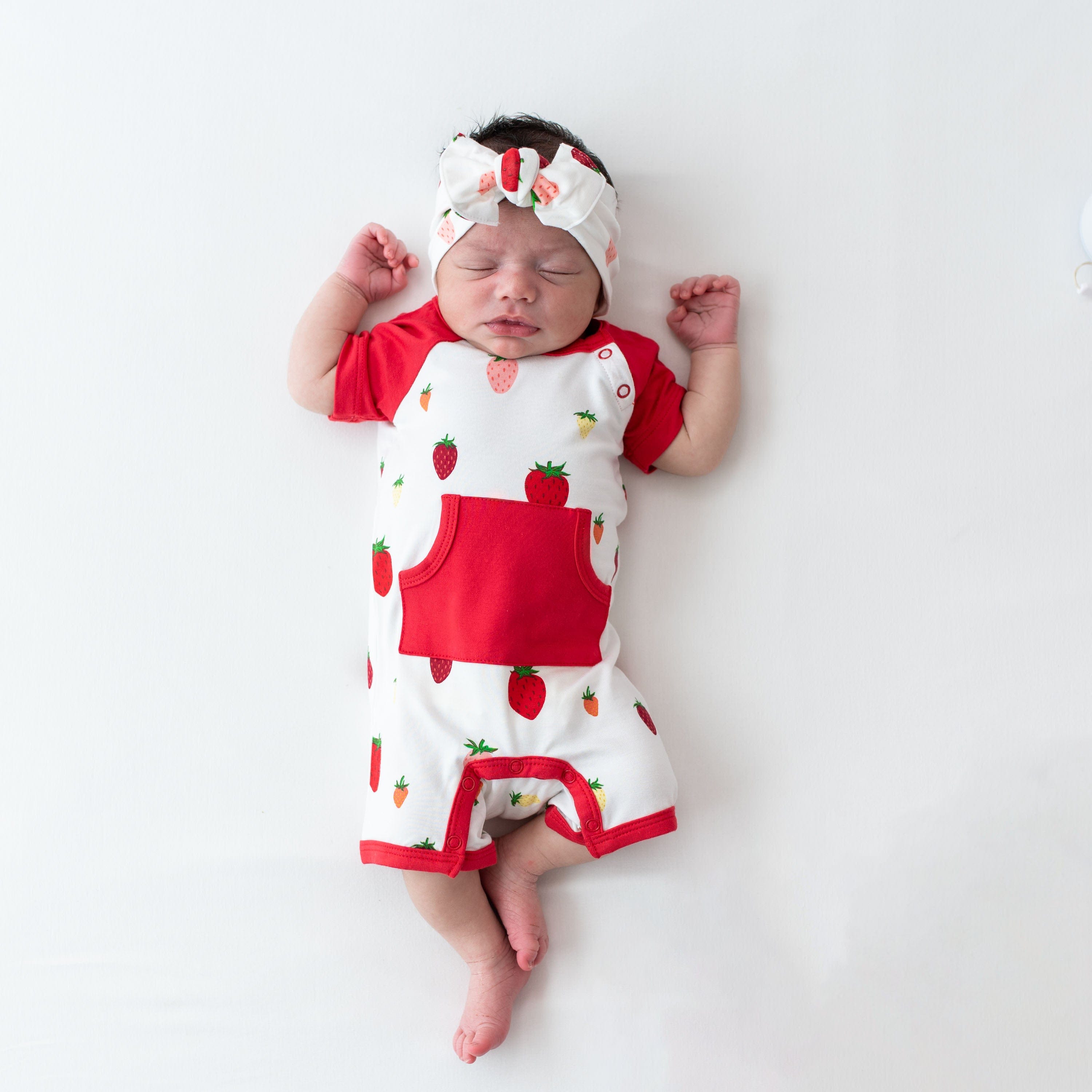 Infant wearing Kyte Baby Shortall in Strawberry