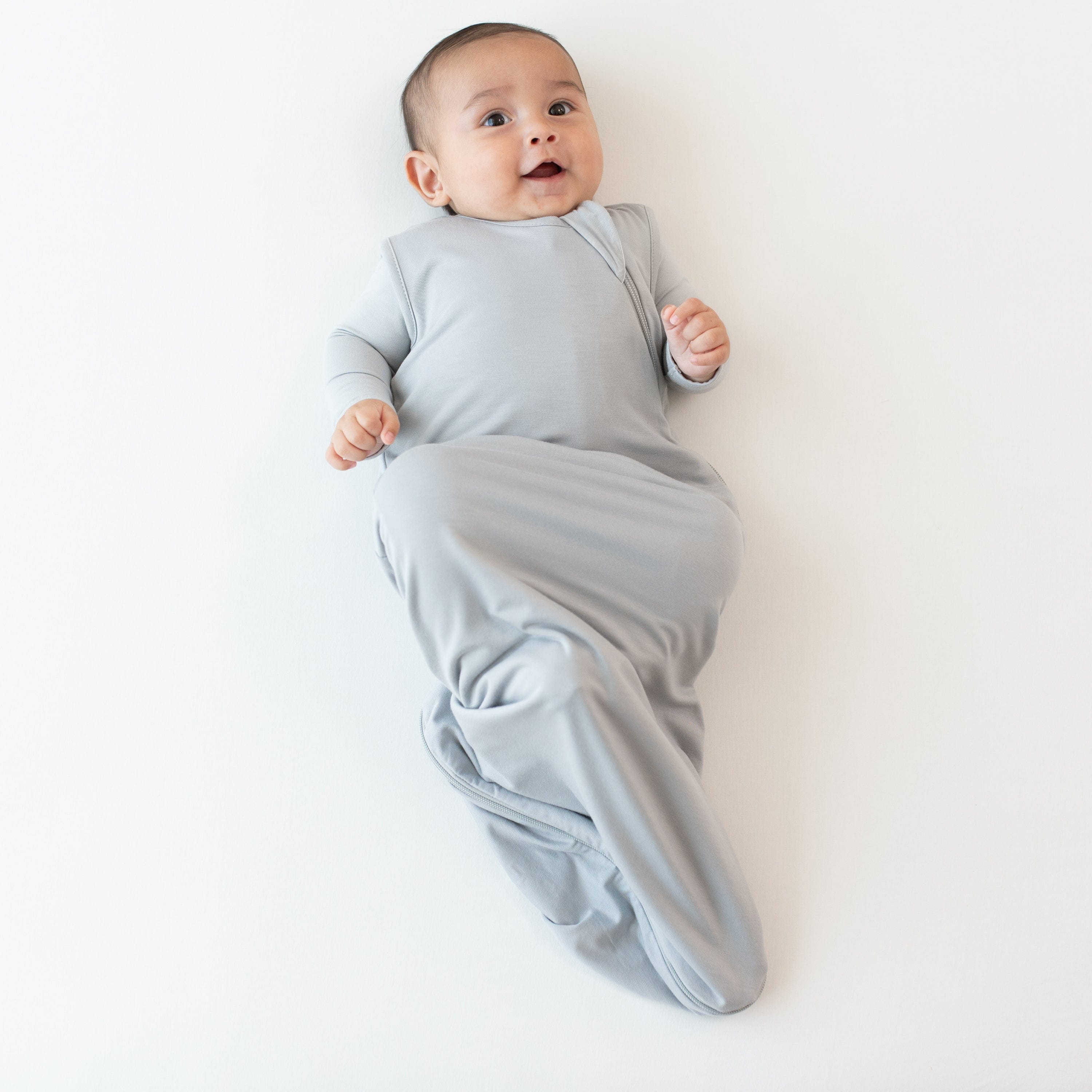 Infant modeling the 0.5 Tog Sleep Bag in Storm with a Storm long sleeve romper underneath