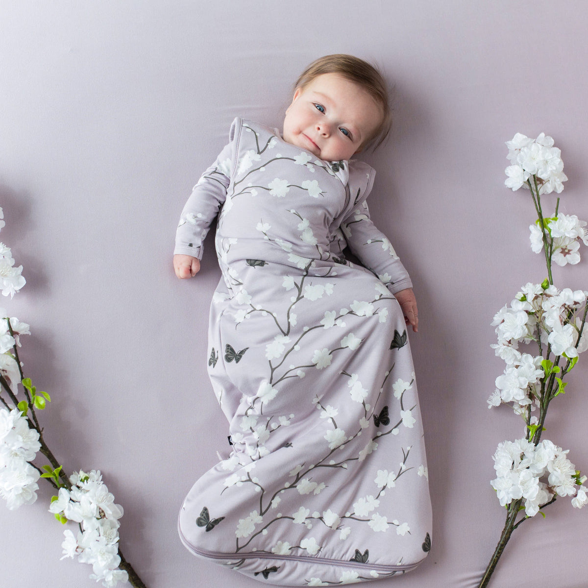 Infant wearing Kyte Baby Sleep Bag in Cherry Blossom 1.0