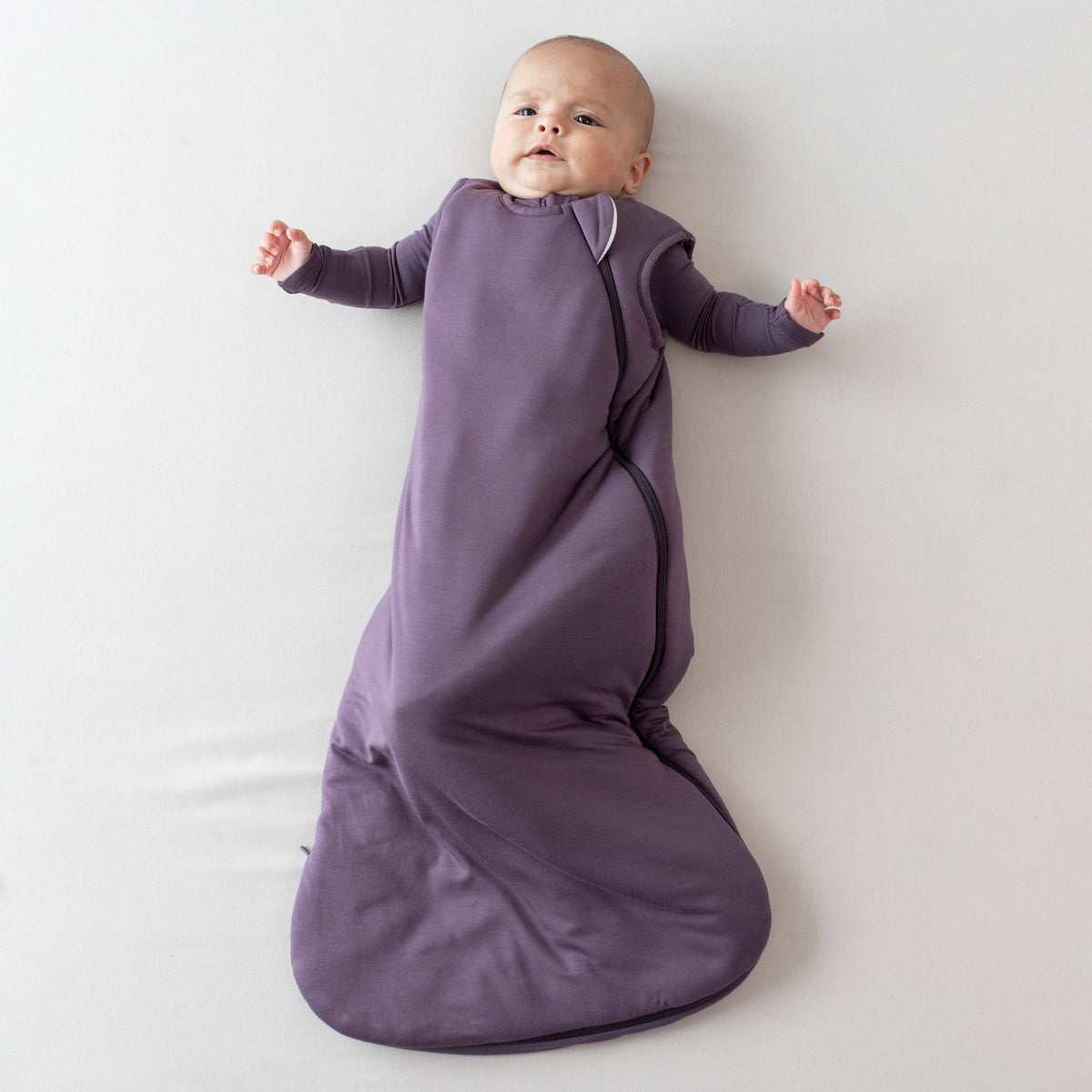 Infant modeling the 1.0 Sleep Bag in Currant wearing a Currant long sleeve romper underneath
