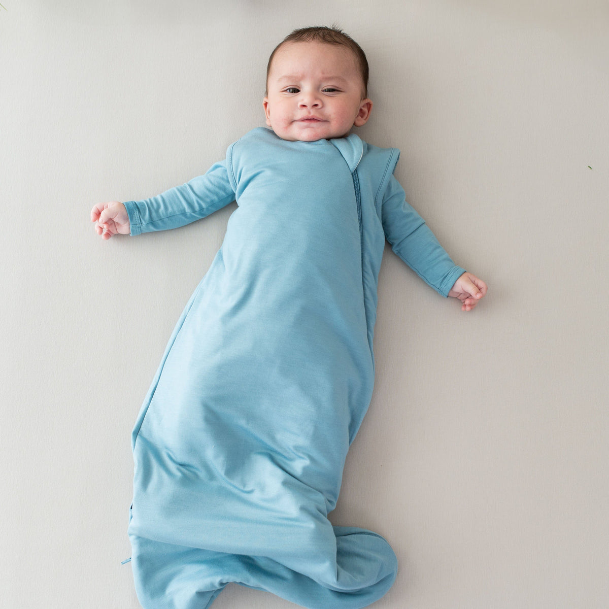 Infant wearing Kyte Baby Sleep Bag in Dusty Blue 1.0