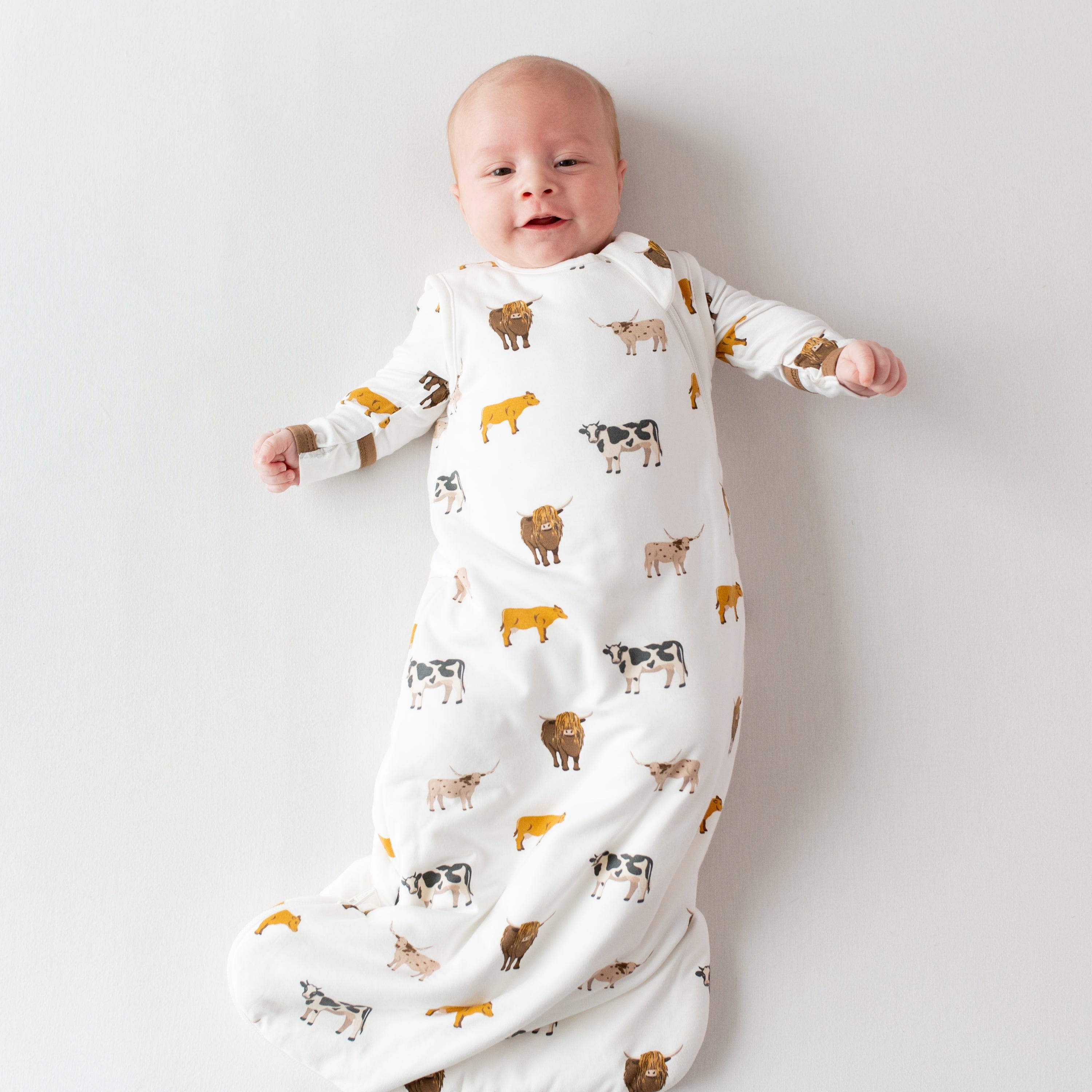 Infant wearing Kyte Baby Sleep Bag in Moo 1.0