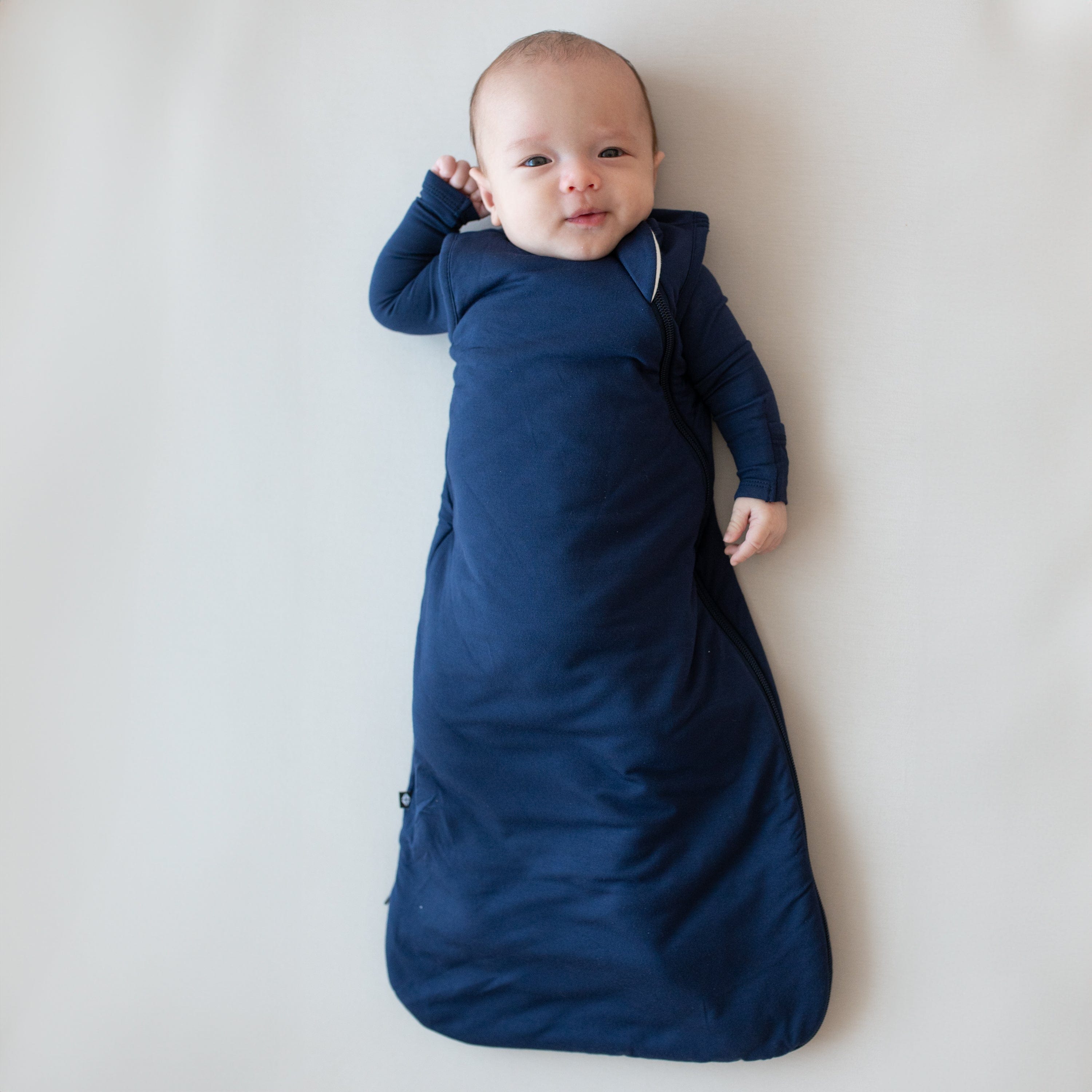 Baby modeling the Sleep Bag in Navy 1.0 wearing a Navy long sleeve romper underneath