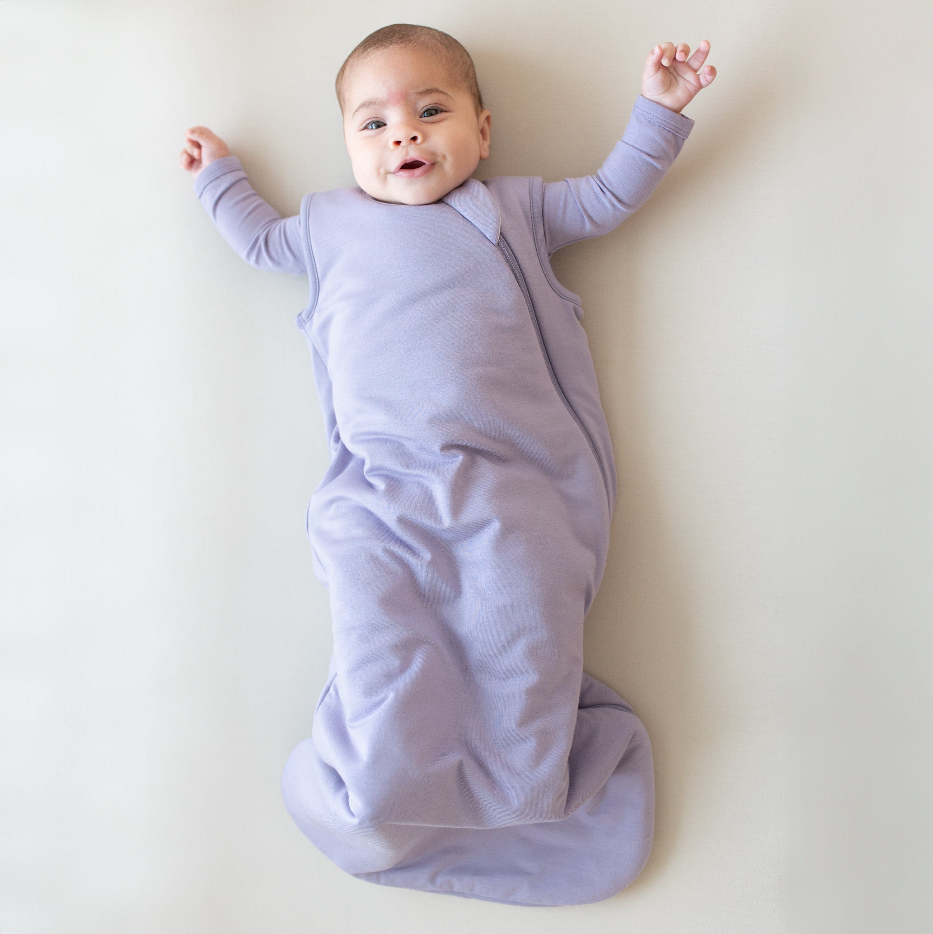 Infant modeling the Sleep Bag in Taro 1.0 with a Taro long sleeve romper underneath