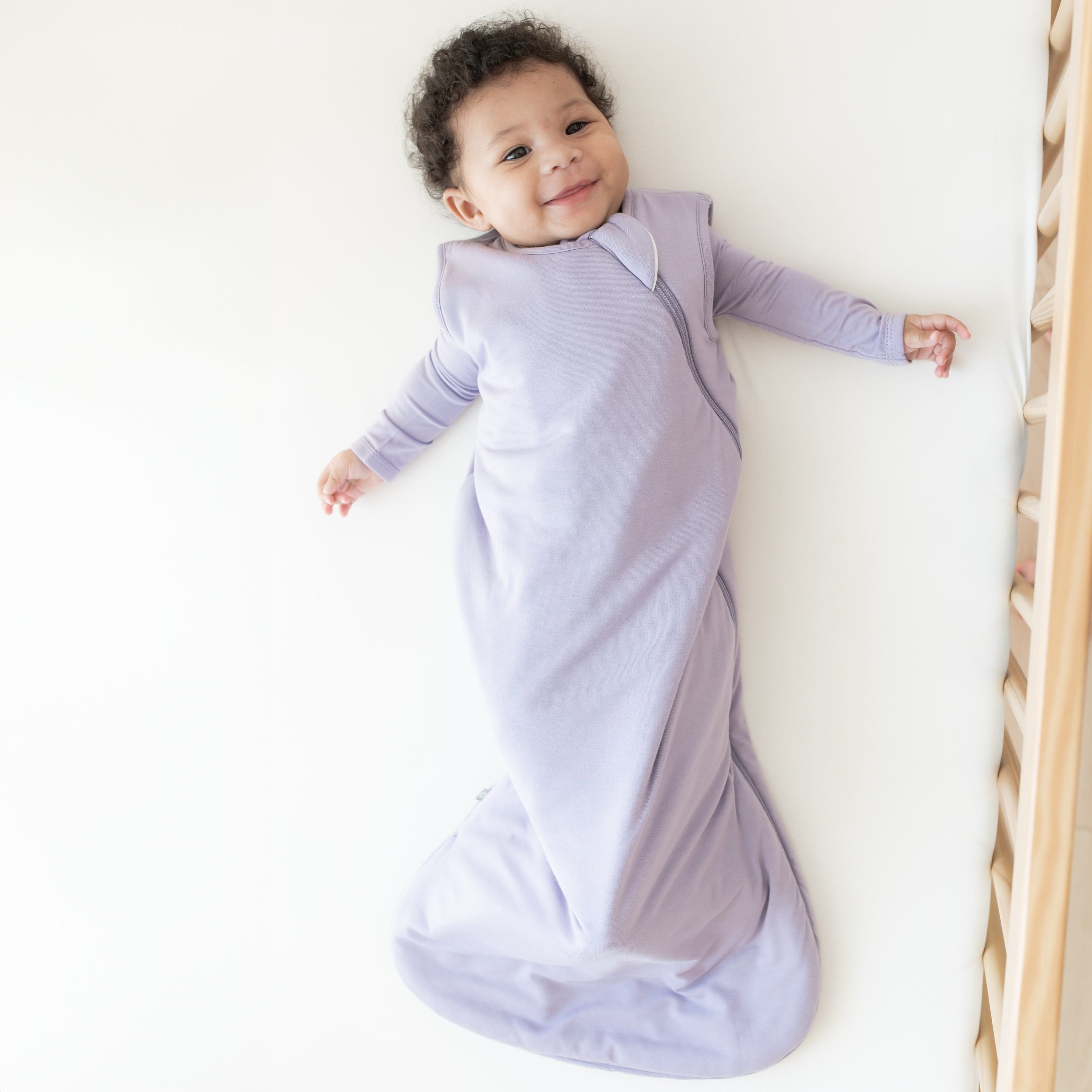 Smiling infant wearing the Sleep Bag in Taro 1.0 TOG