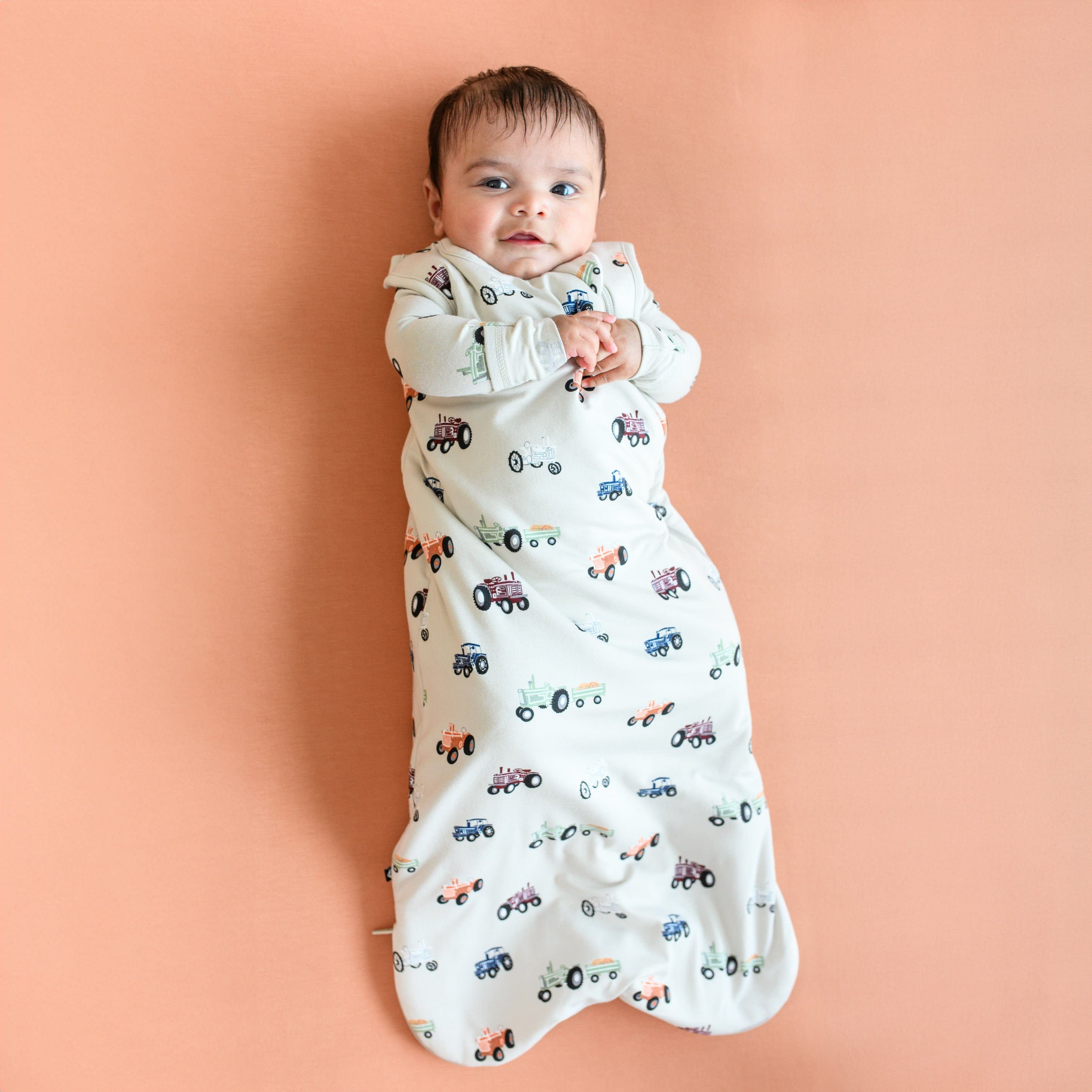 Infant wearing Kyte Baby Sleep Bag in Tractor