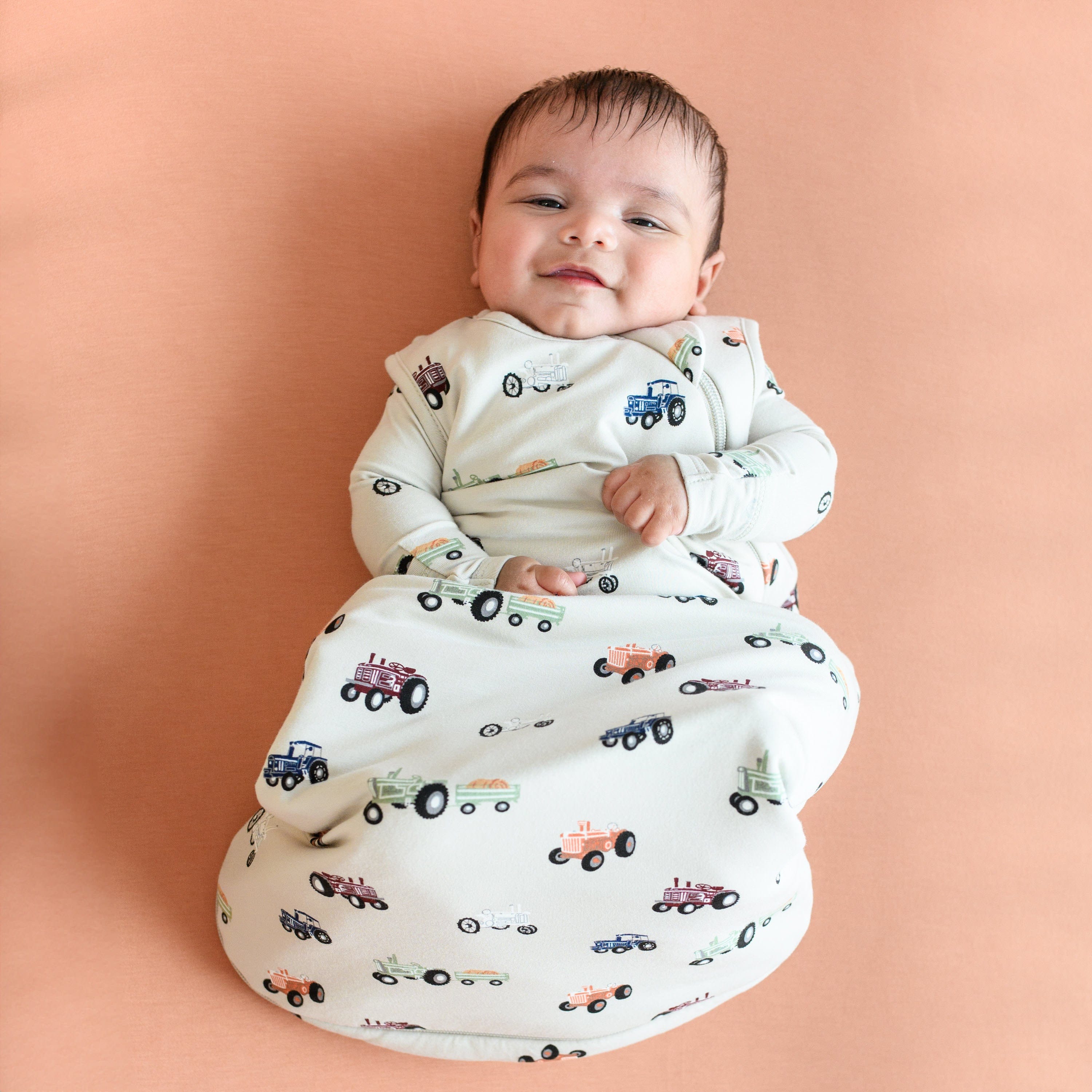 Infant wearing Kyte Baby bamboo Sleep Bag in Tractor