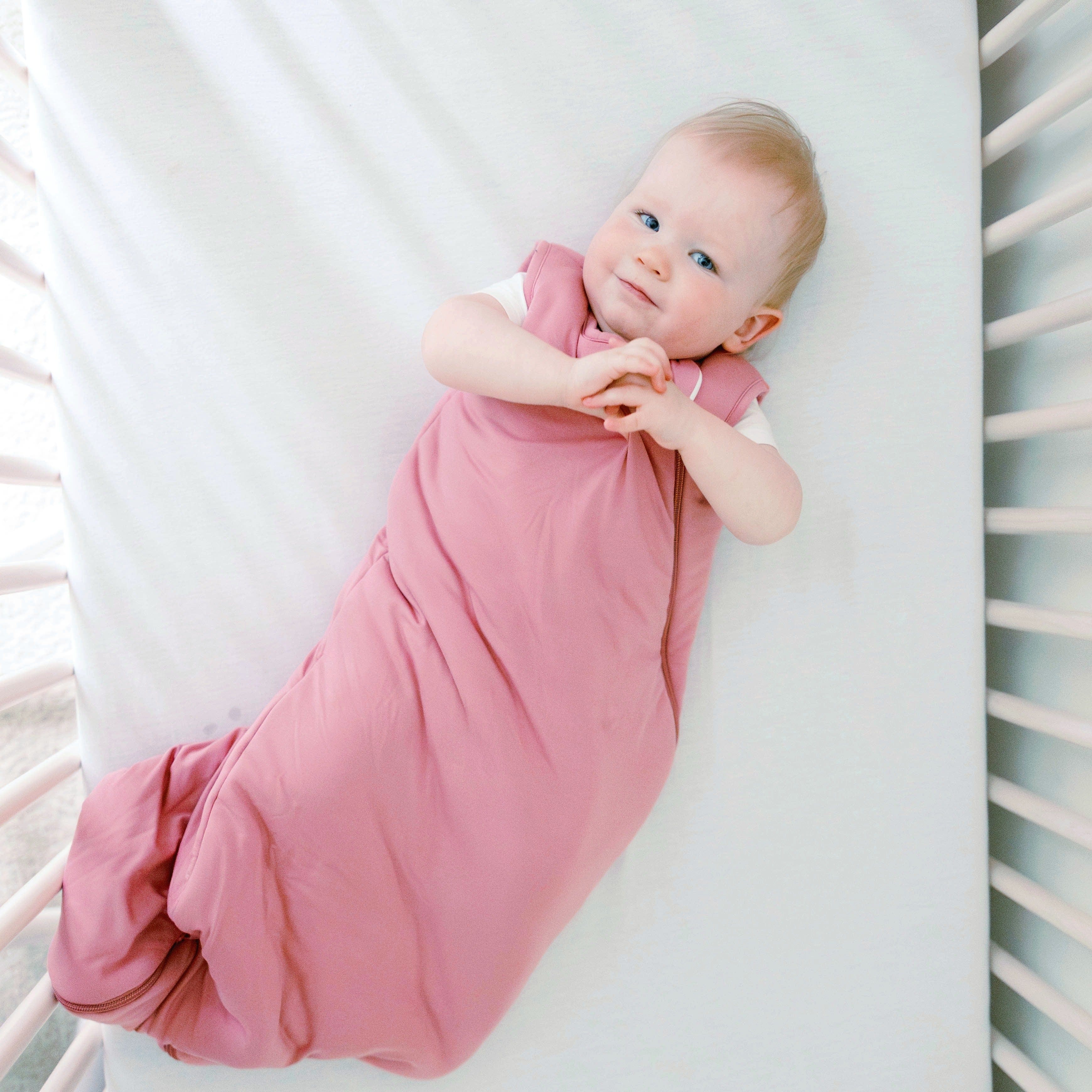 Baby wearing the Sleep Bag in Apple Blossom 2.5 with a white short sleeve bodysuit