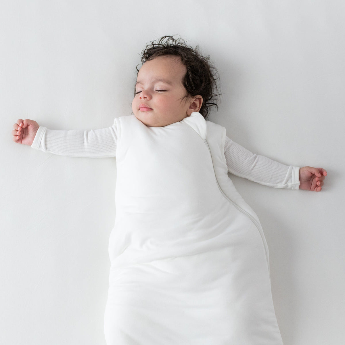 Sleeping baby wearing Kyte Baby bamboo Sleep Bag in Cloud 2.5 with matching Long Sleeve Bodysuit underneath