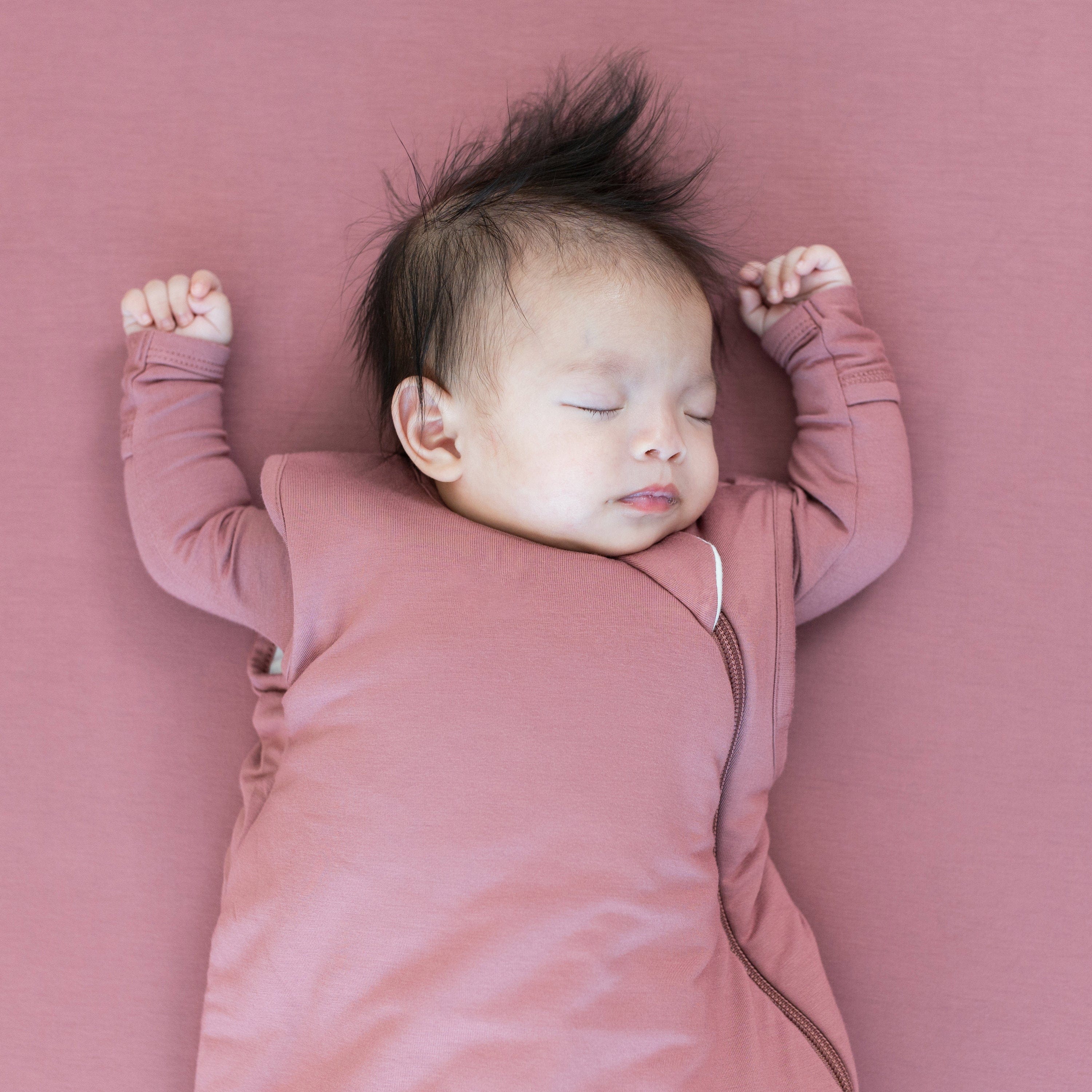 Newborn sleeping in Kyte Baby Sleep Bag in Dusty Rose 2.5