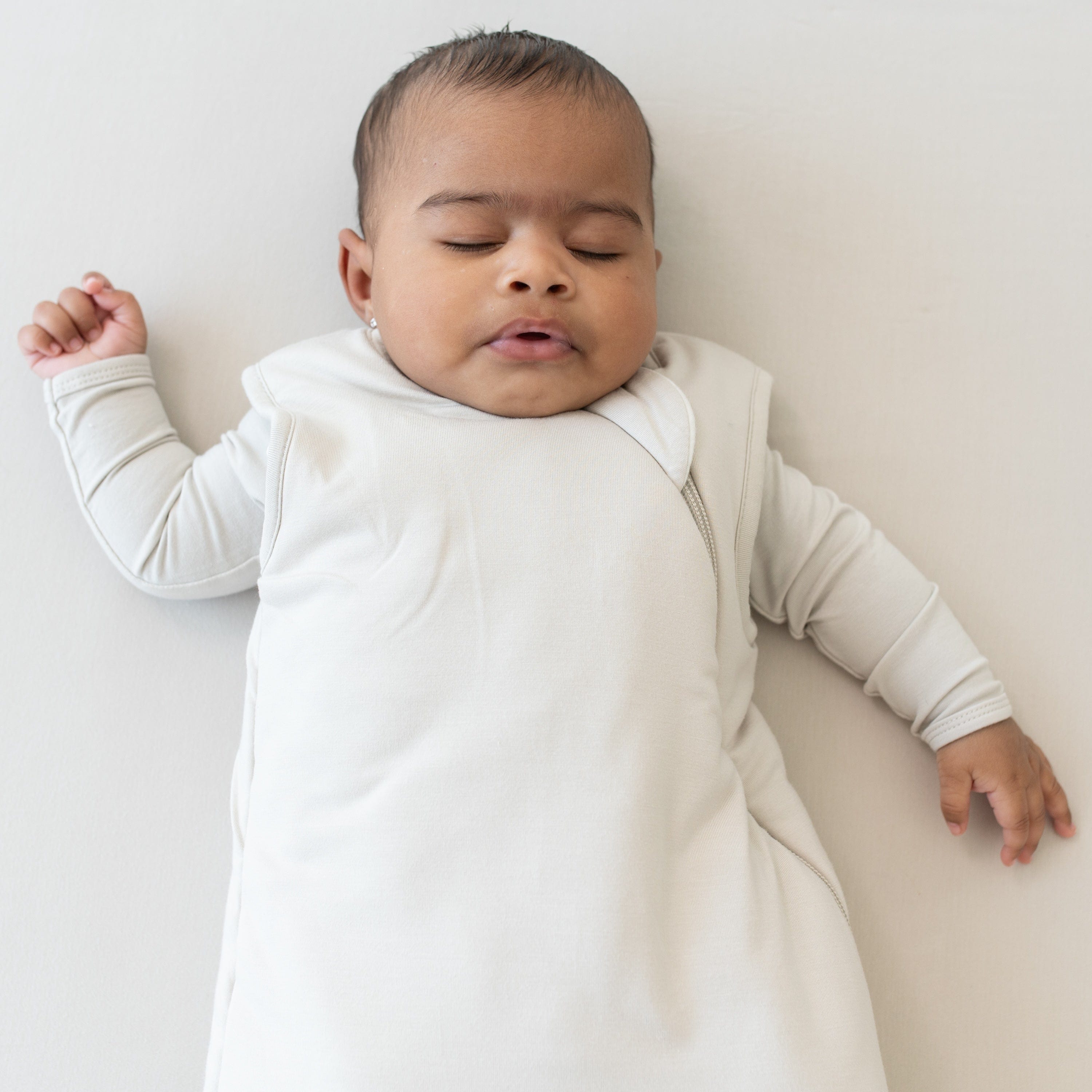 Close up of baby sleeping on an Oat surface while wearing the Sleep Bag in Oat 2.5