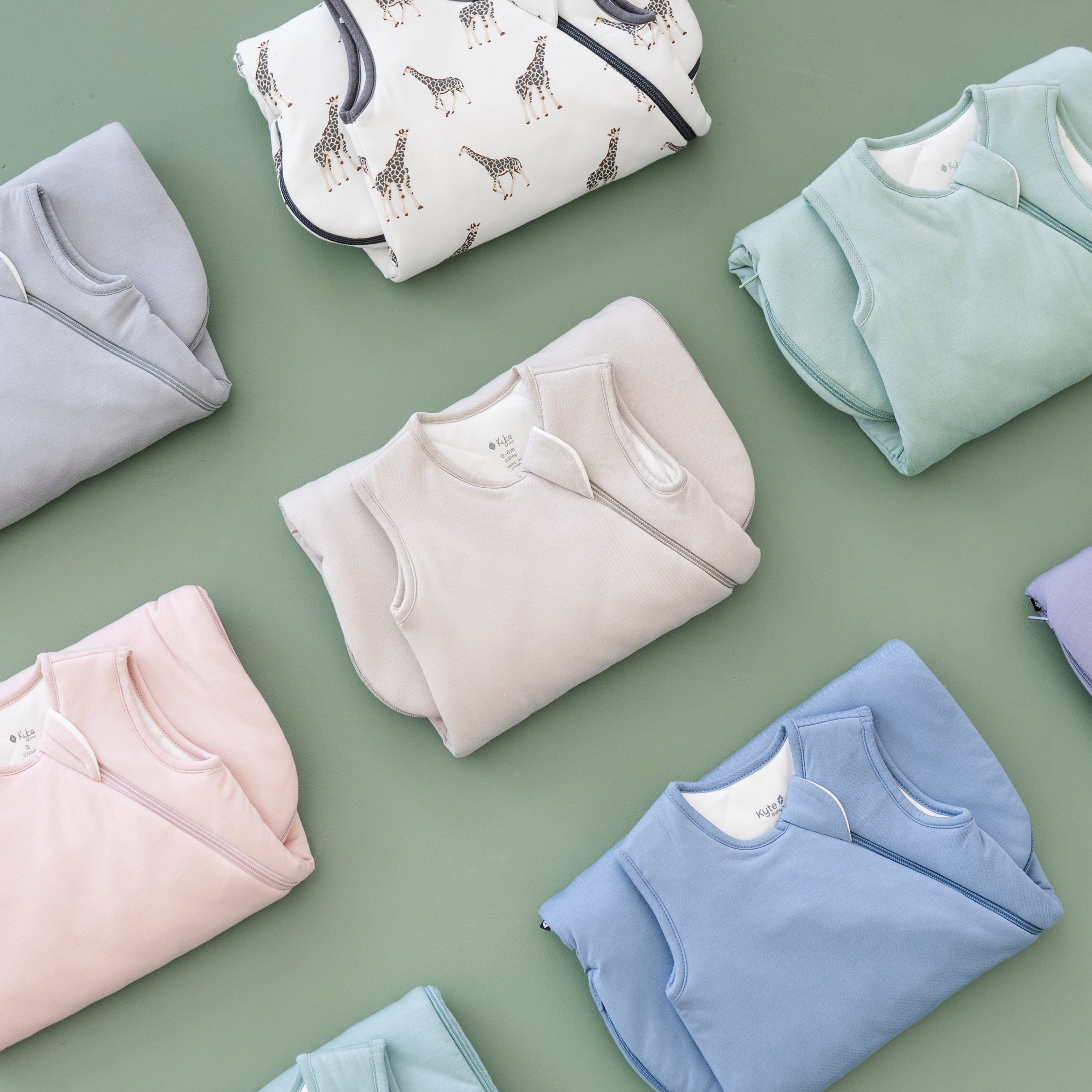 Different colored Kyte Sleep Bags 2.5 TOG folded in half on a sage surface