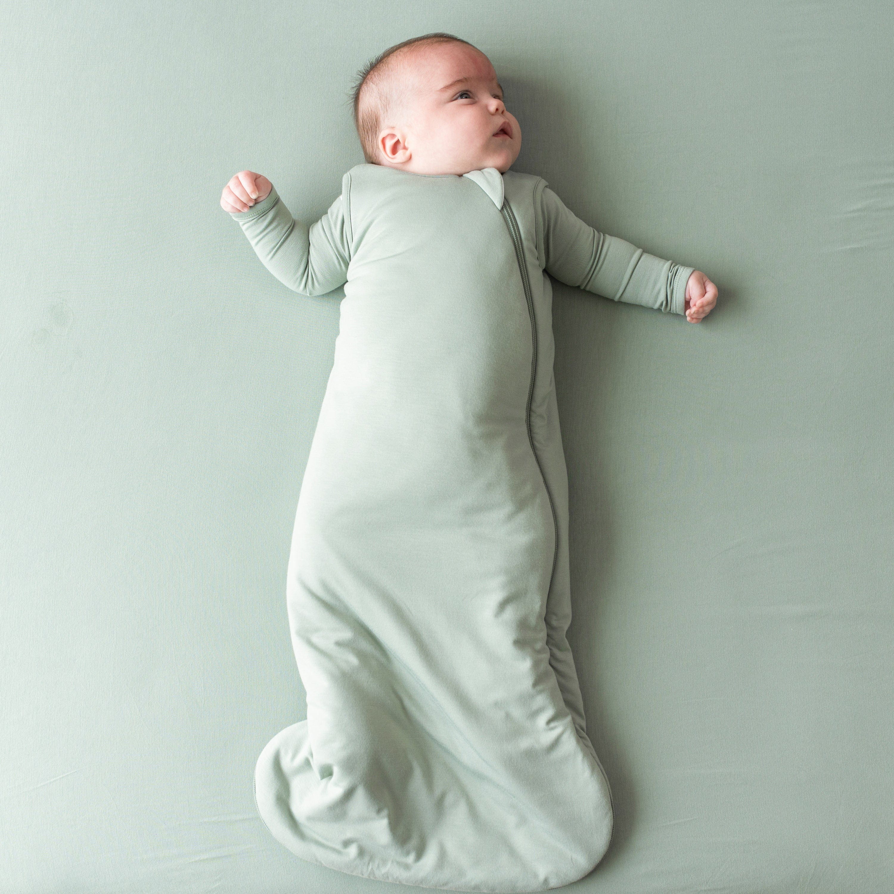 Infant wearing Kyte Baby Sleep Bag in Thyme 2.5