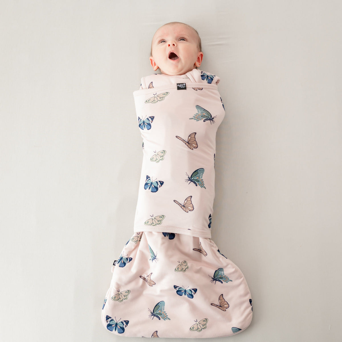 Yawning baby swaddled in the Sleep Bag Swaddler in Blush Butterfly 1.0