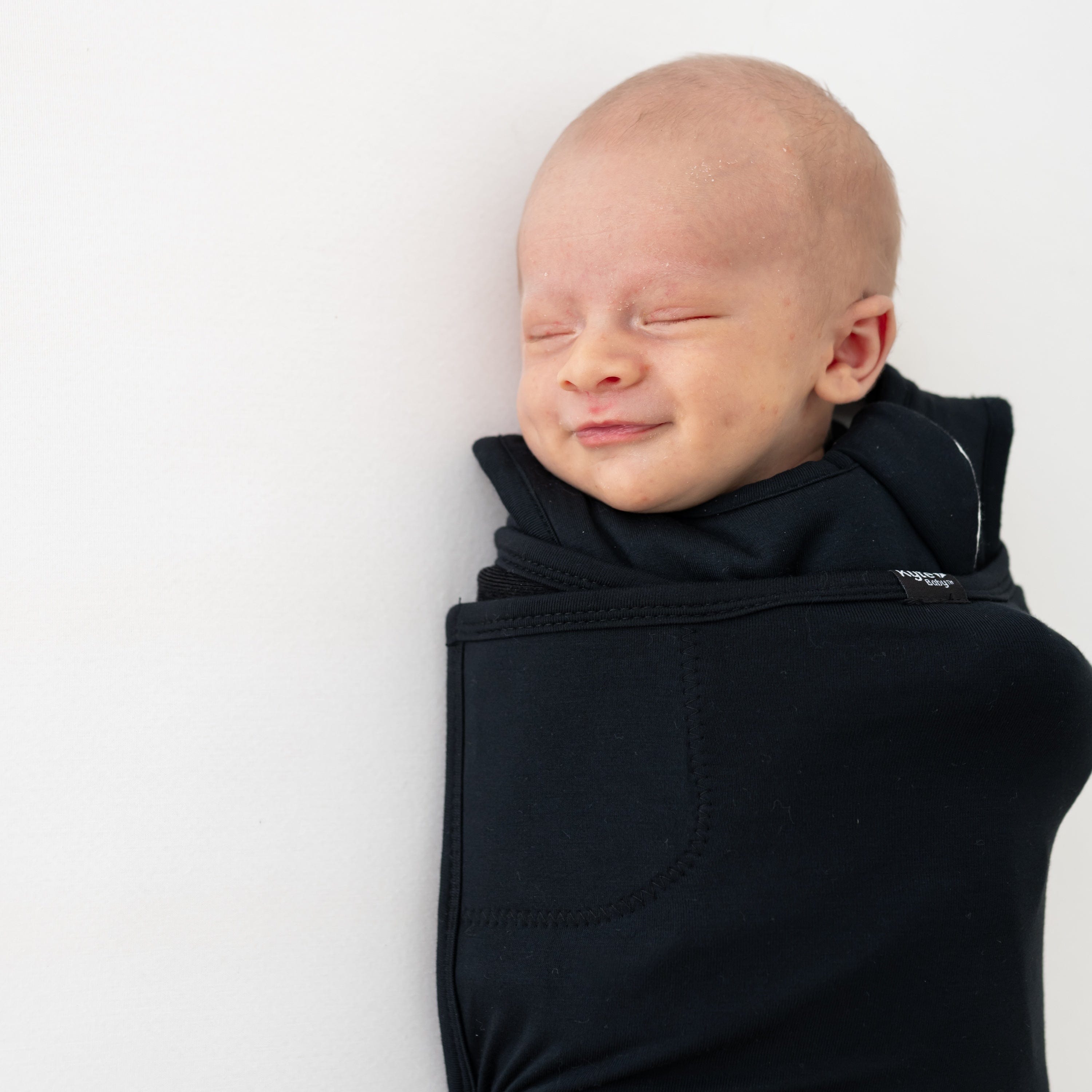 Close up of sleeping newborn wearing the Sleep Bag Swaddler in Midnight 1.0