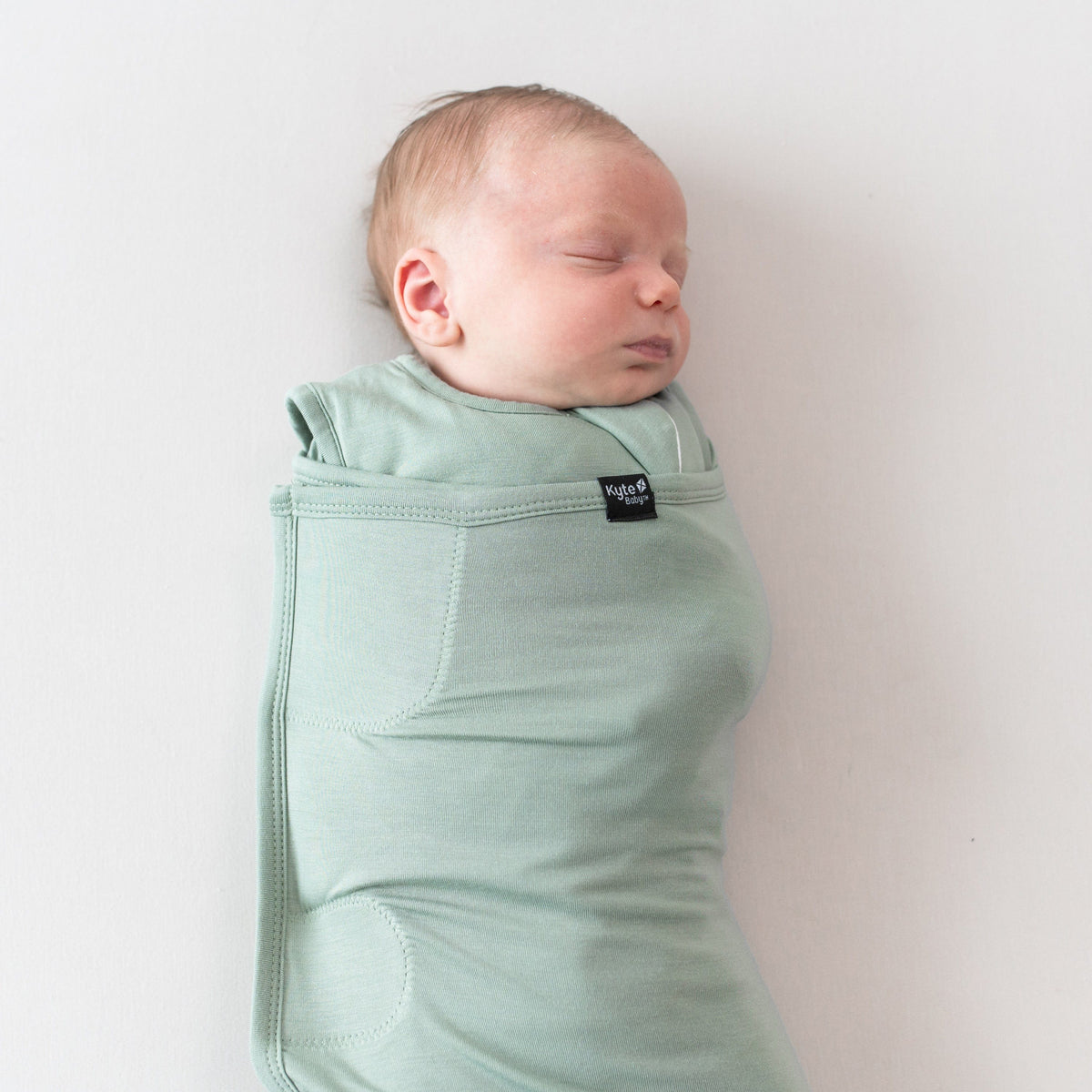 Sleeping baby swaddled in Sleep Bag Swaddler in Thyme 1.0