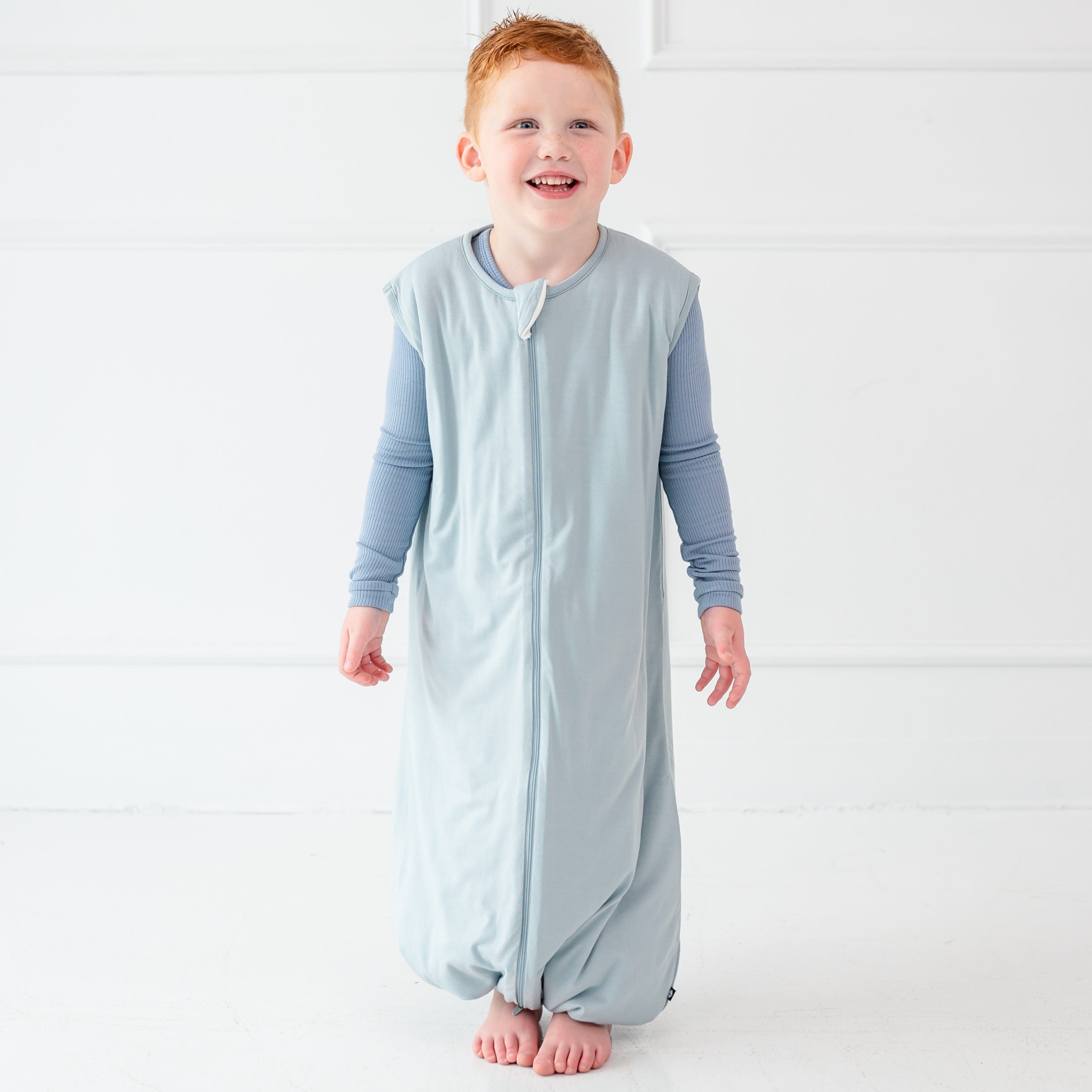 Child model smiling wearing the Sleep Bag Walker in Fog 1.0
