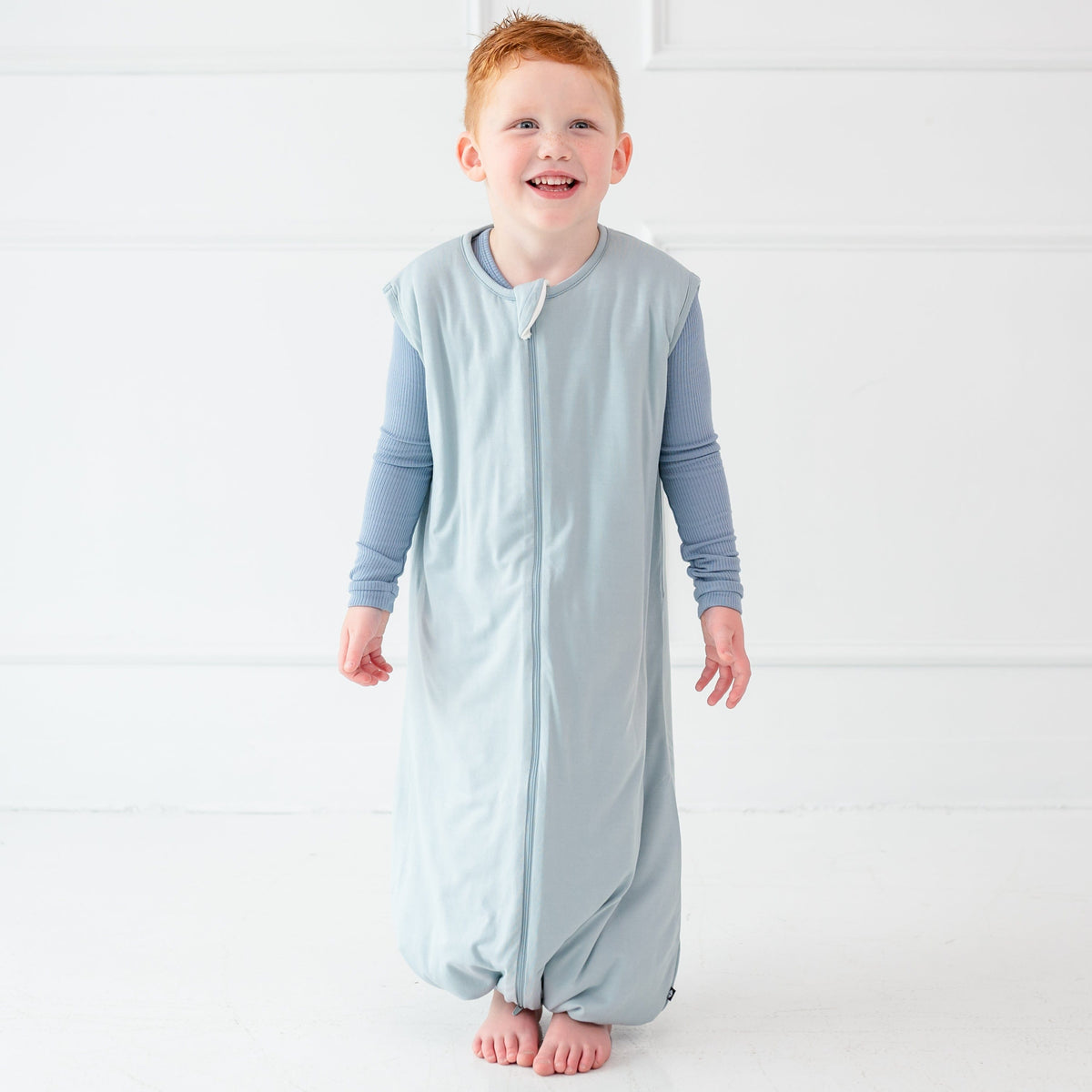 Child model smiling wearing the Sleep Bag Walker in Fog 1.0
