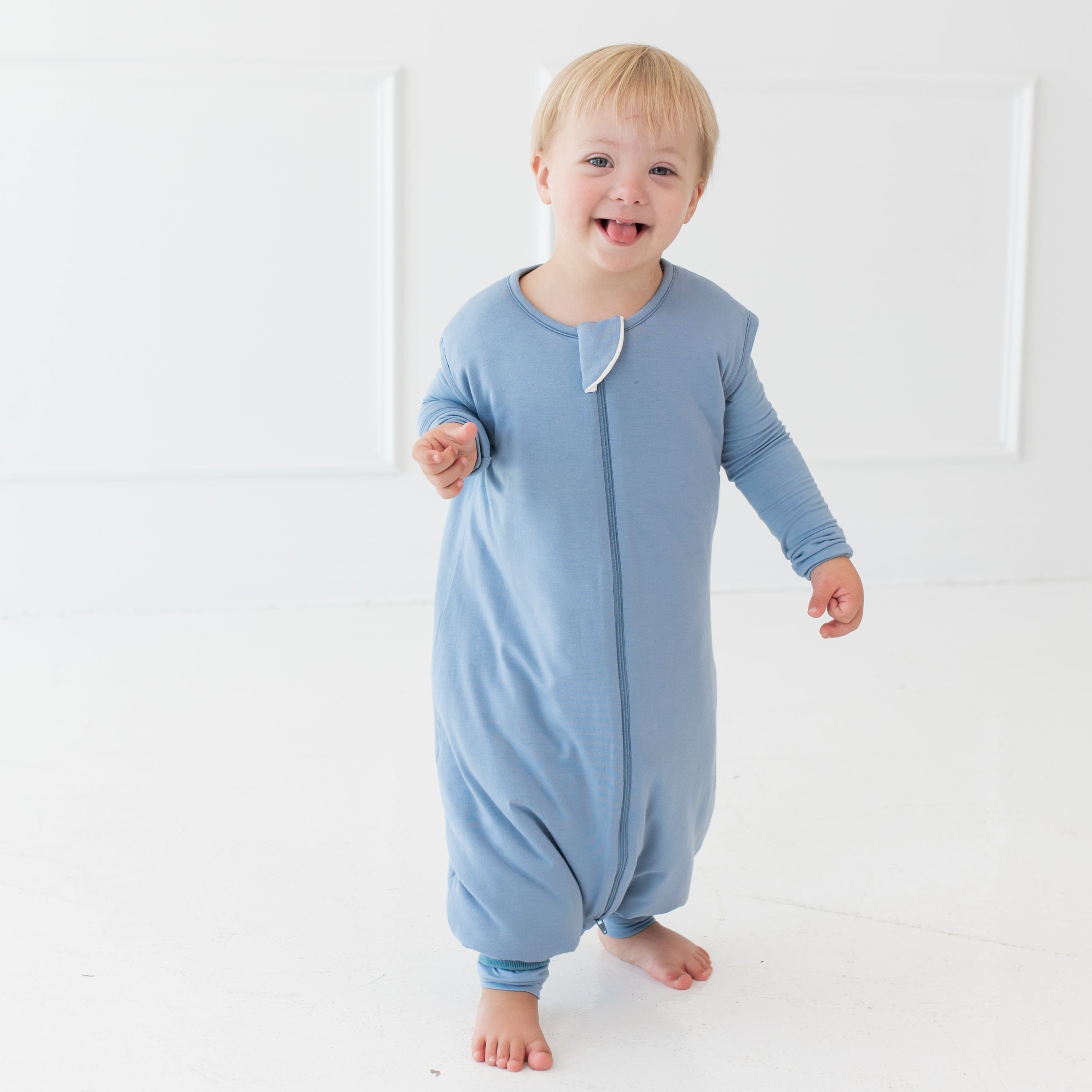 Smiling boy standing while wearing the Sleep Bag Walker in Slate 1.0