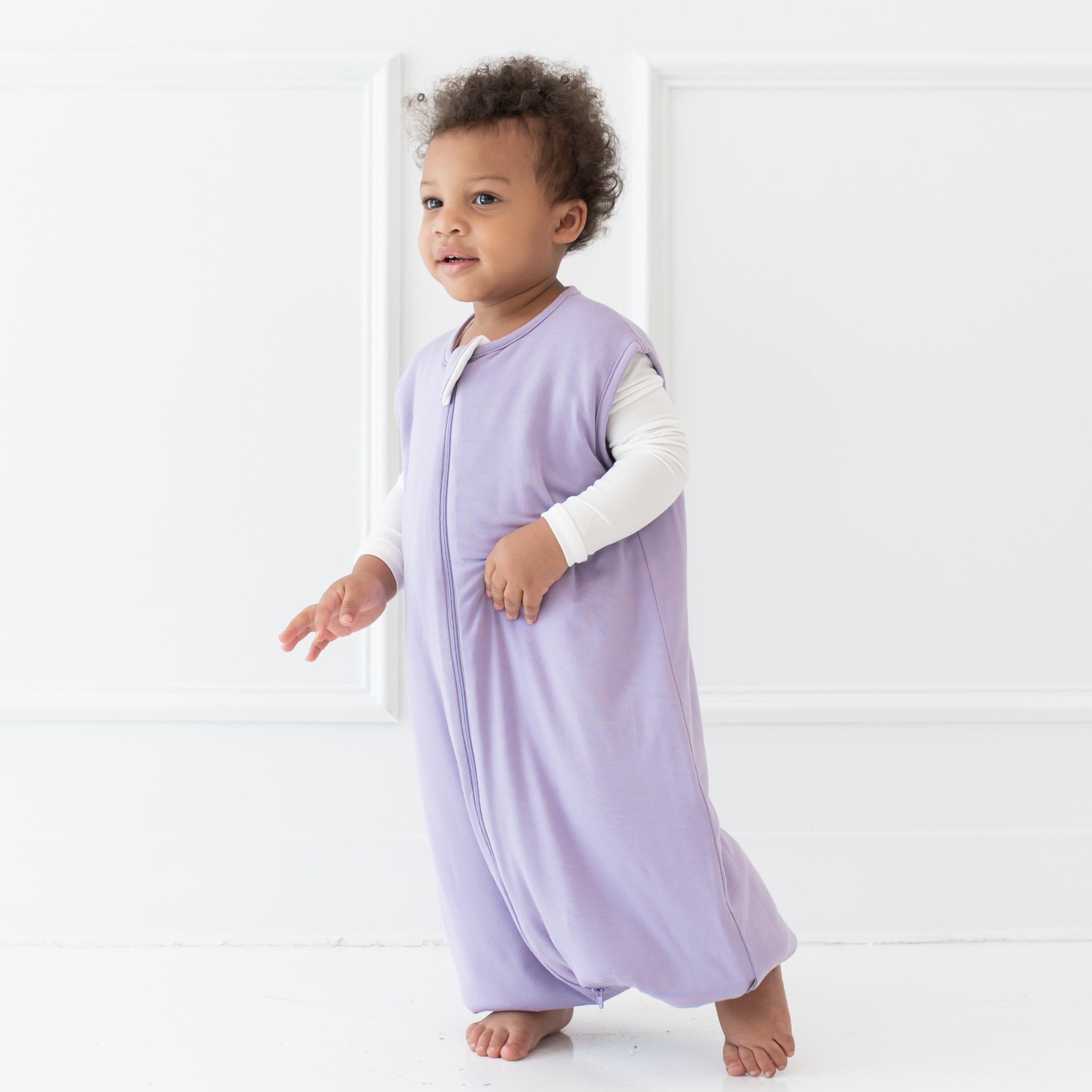 Young child walking wearing the Sleep Bag Walker in Taro 1.0