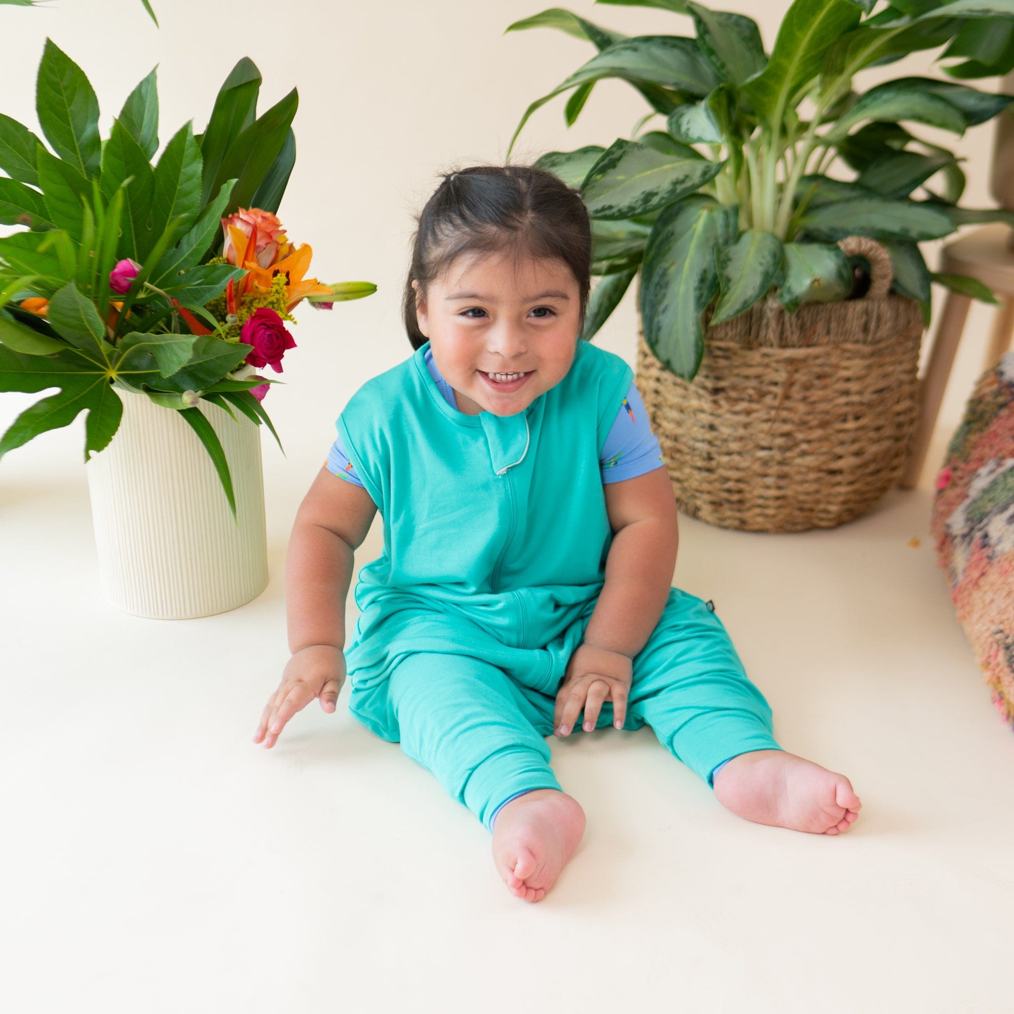 Smiling model sitting while wearing the Sleep Bag Walker in Caribbean 0.5