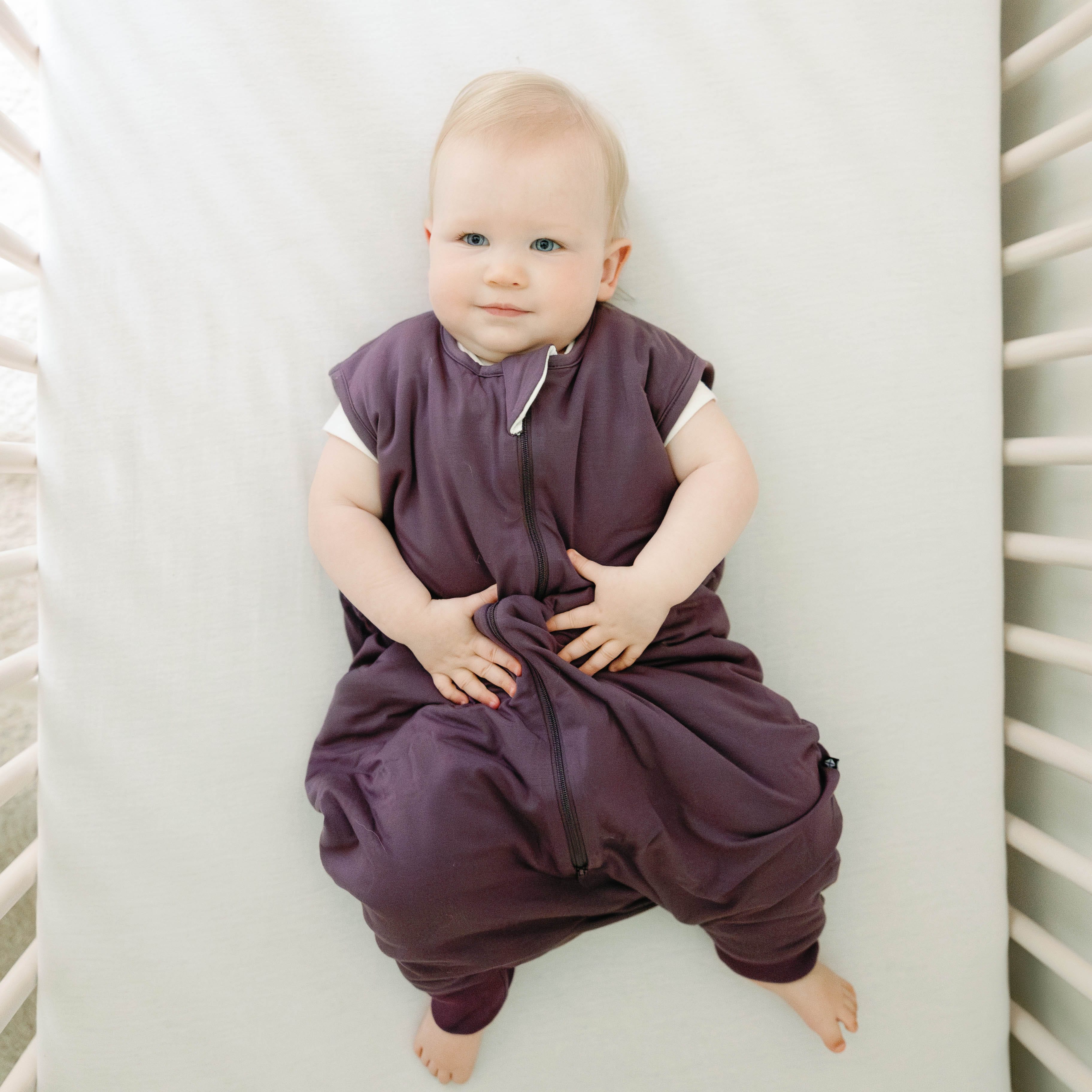 Toddler model laying in a crib wearing the Sleep Bag Walker in Currant 2.5