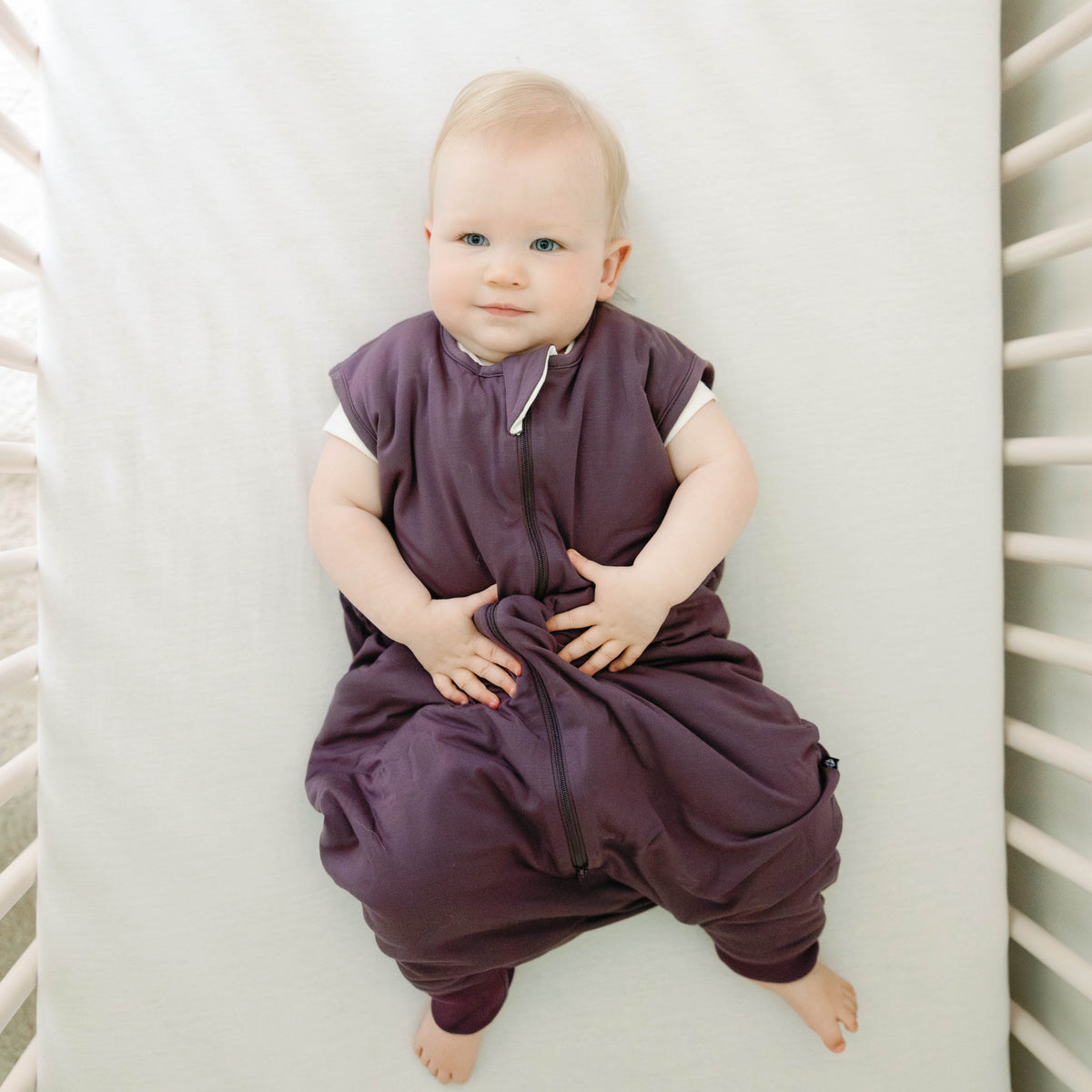 Toddler model laying in a crib wearing the Sleep Bag Walker in Currant 2.5