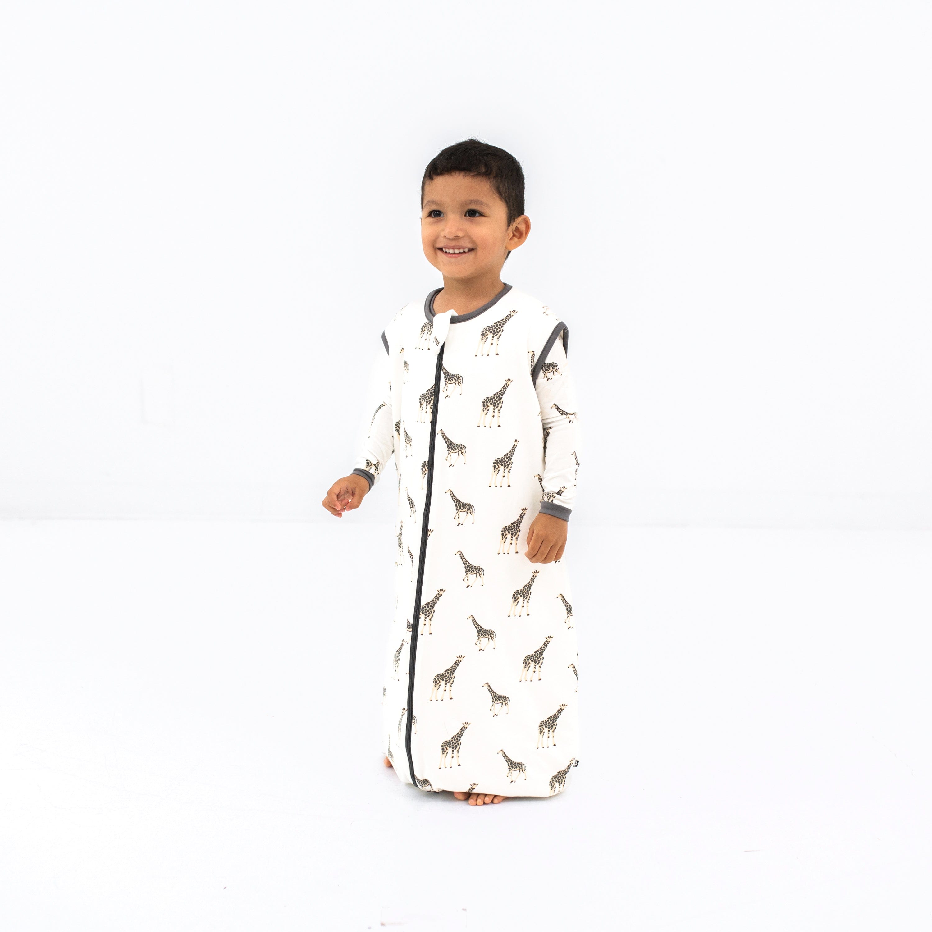 Smiling model looking to the side wearing the Sleep Bag Walker in Giraffe 1.0