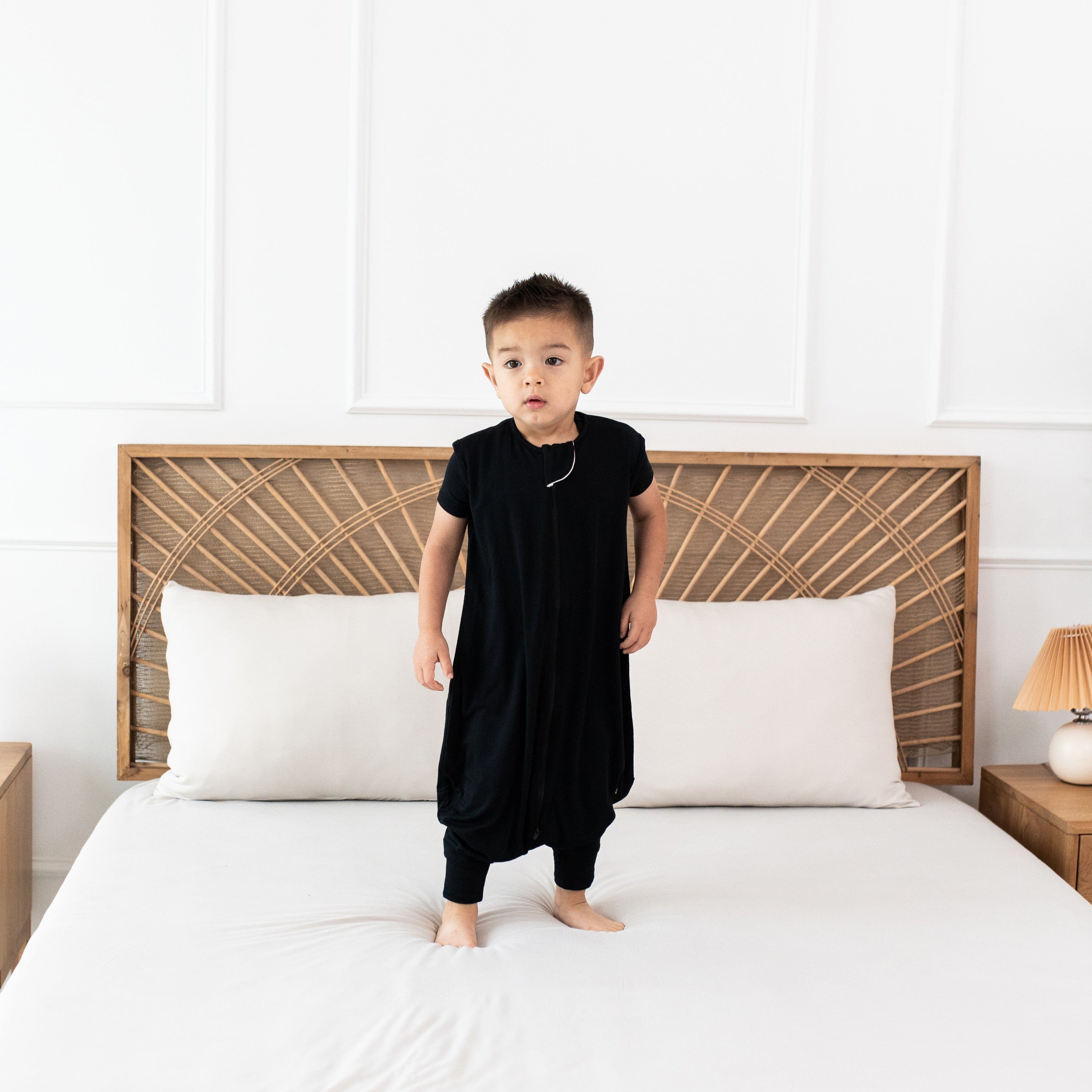 Child model standing on the bed wearing the Sleep Bag Walker in Midnight 0.5
