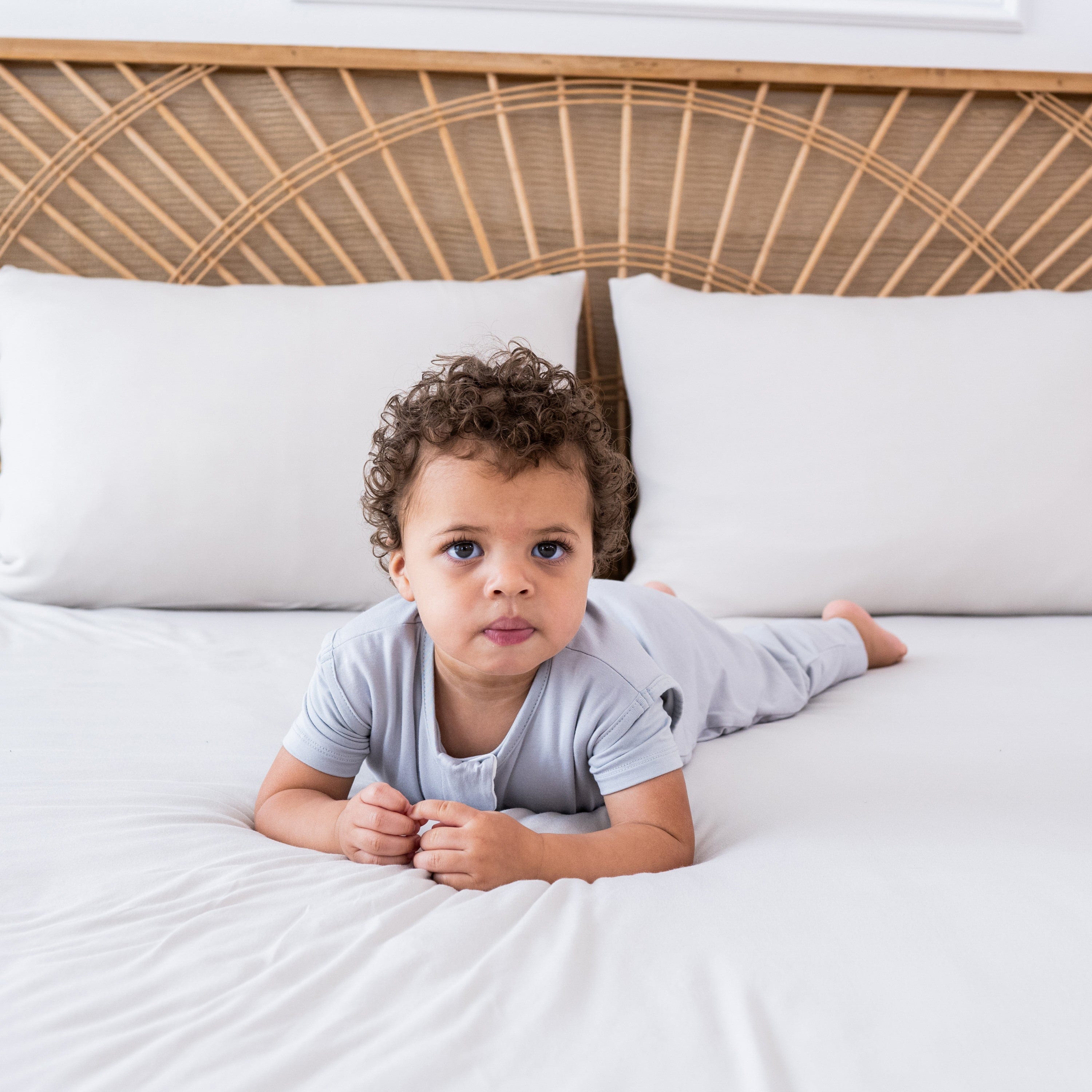 Child model laying on a bed wearing the Sleep Bag Walker in Storm 0.5