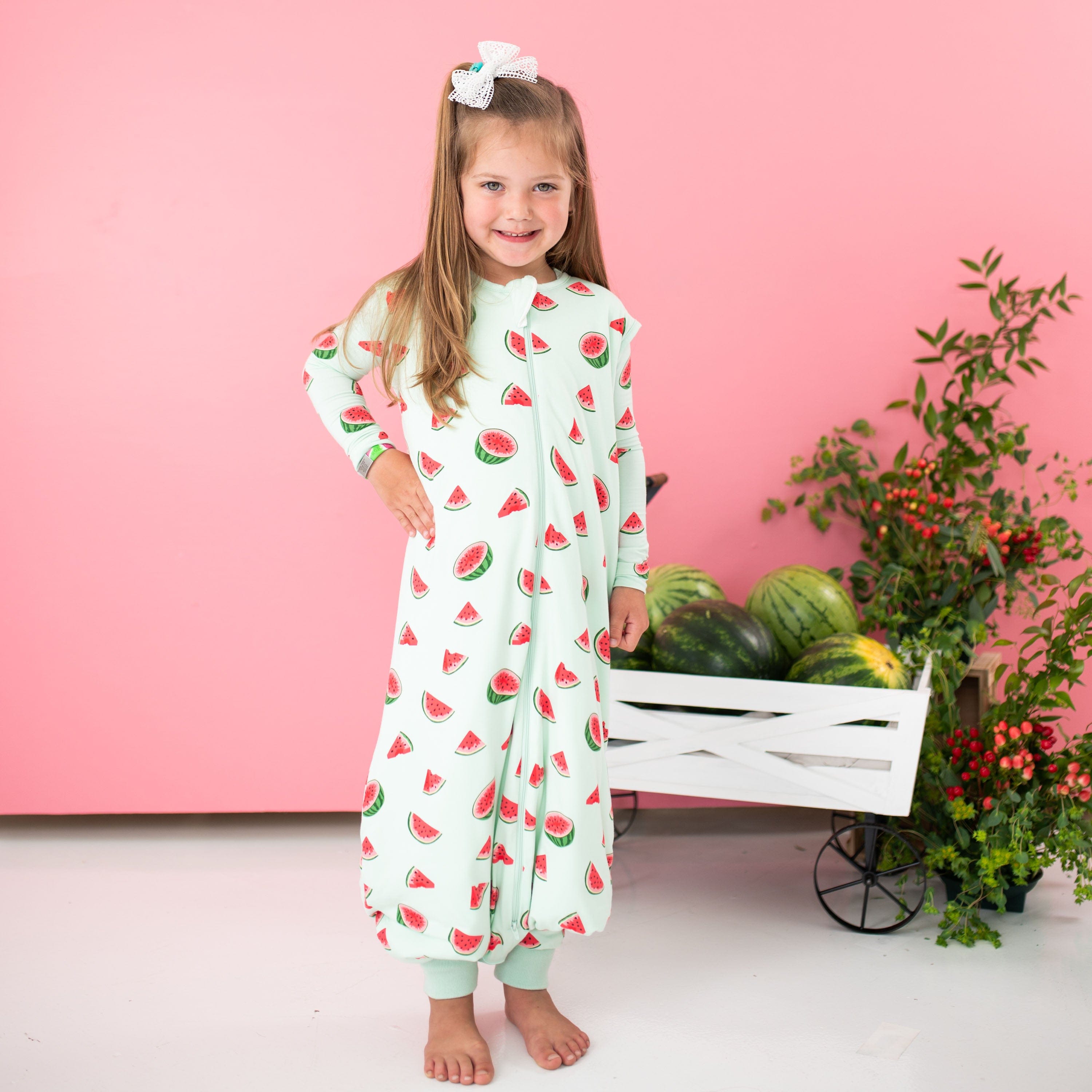 Child model wearing the Sleep Bag Walker in Watermelon 1.0 with one hand on her hip