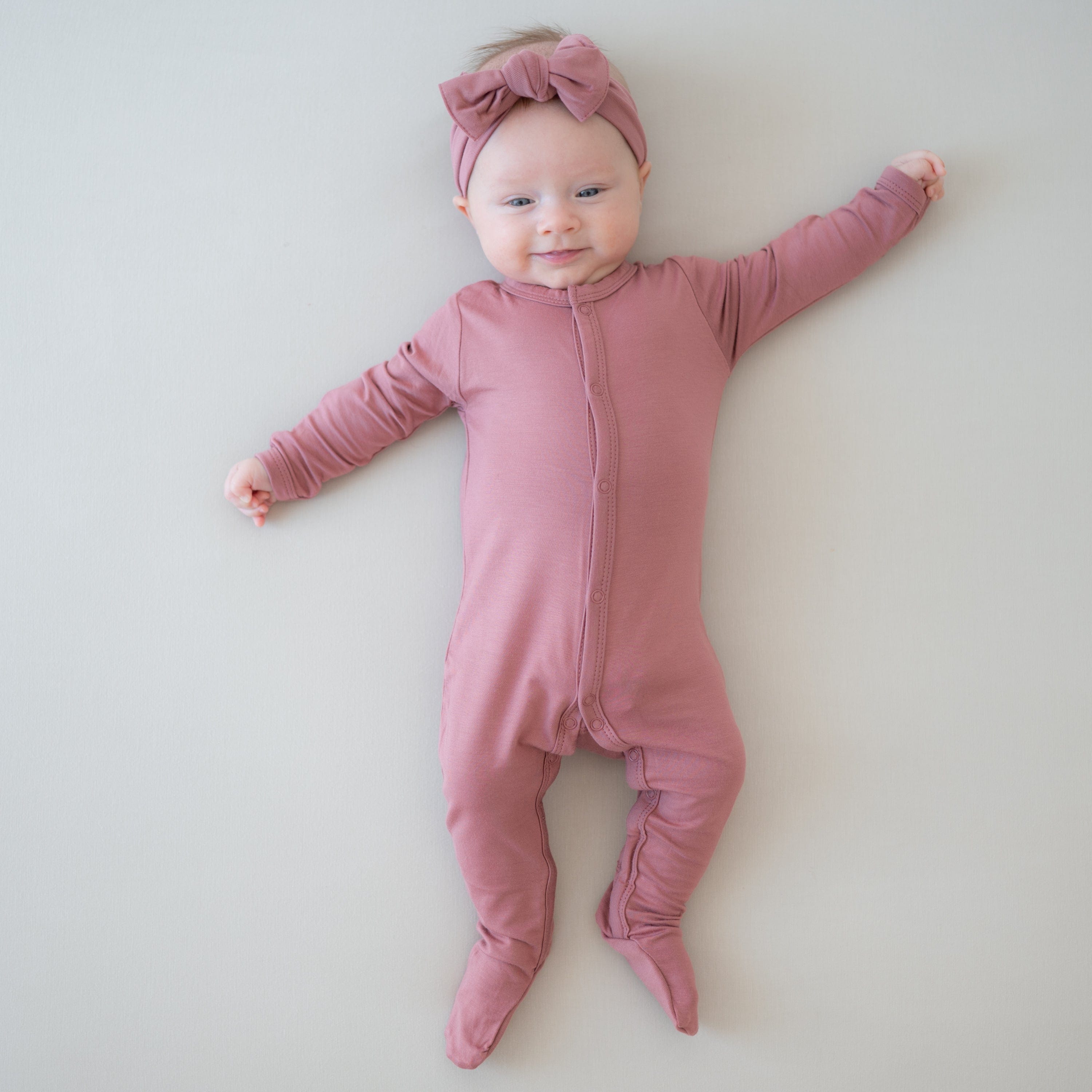Baby wearing Kyte Baby Footie in Dusty Rose