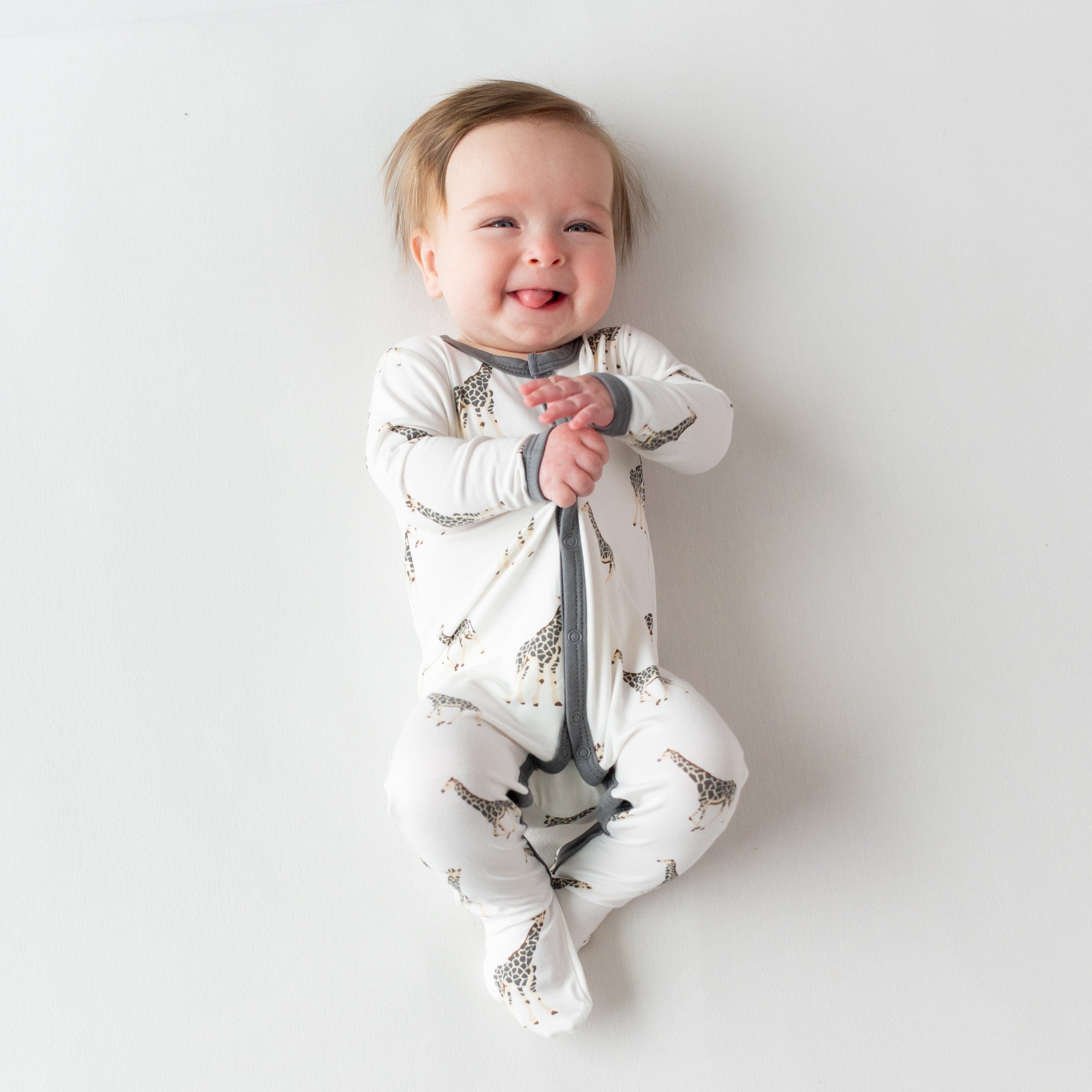 Infant wearing Kyte Baby Snap Footie pajamas in Giraffe
