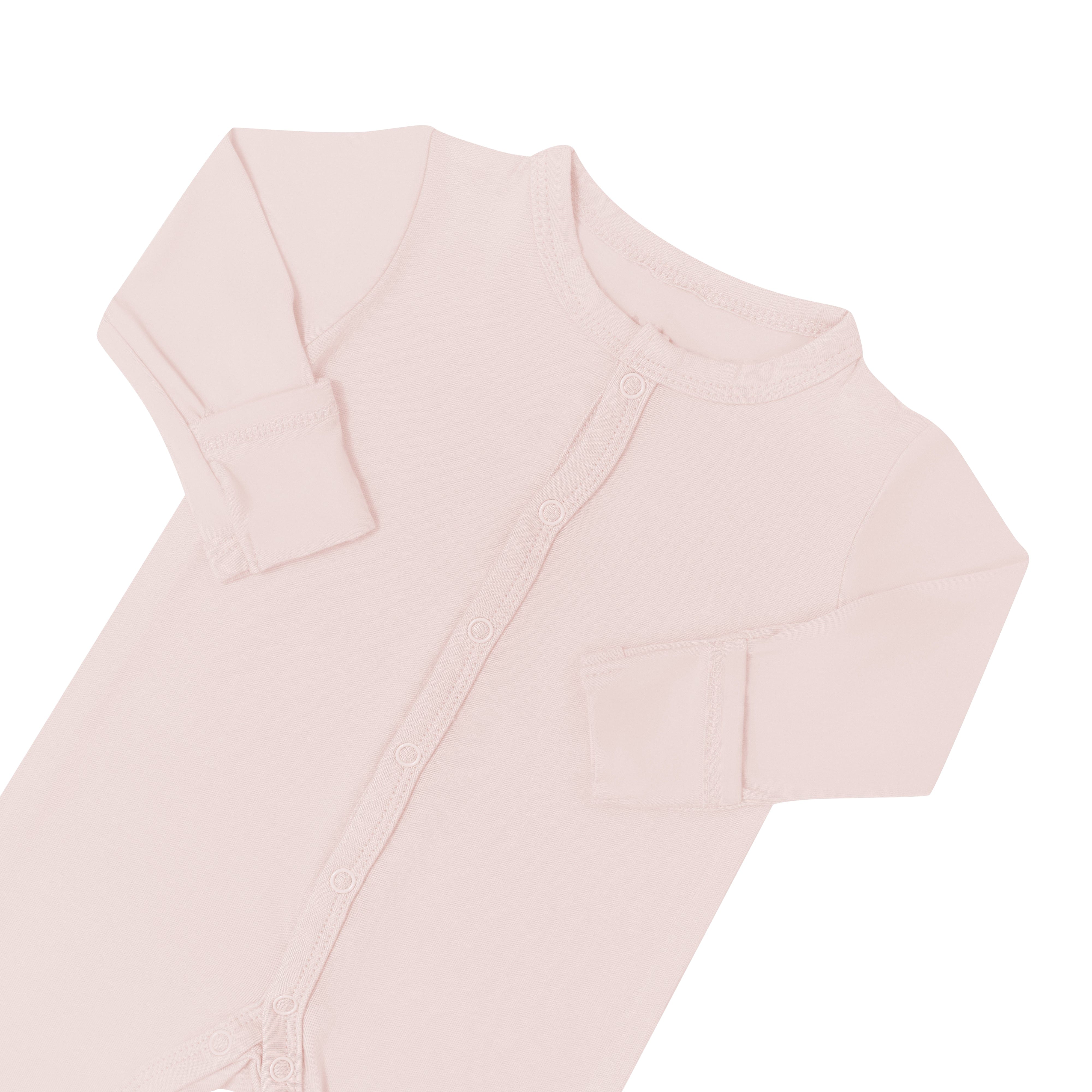 Close up of top portion of Kyte Baby Romper in Blush with arms folded in