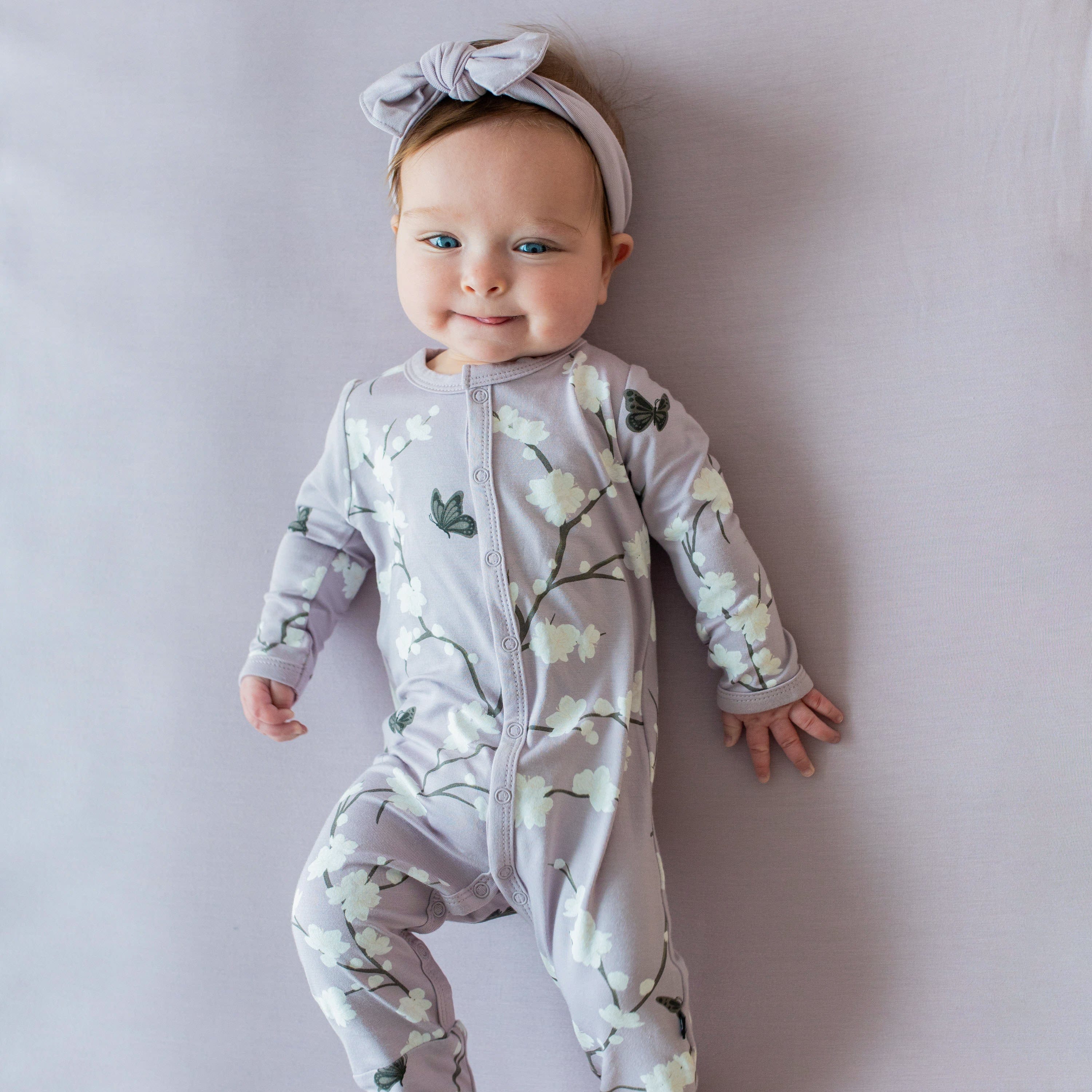 Infant wearing Kyte Baby Romper in Cherry Blossom