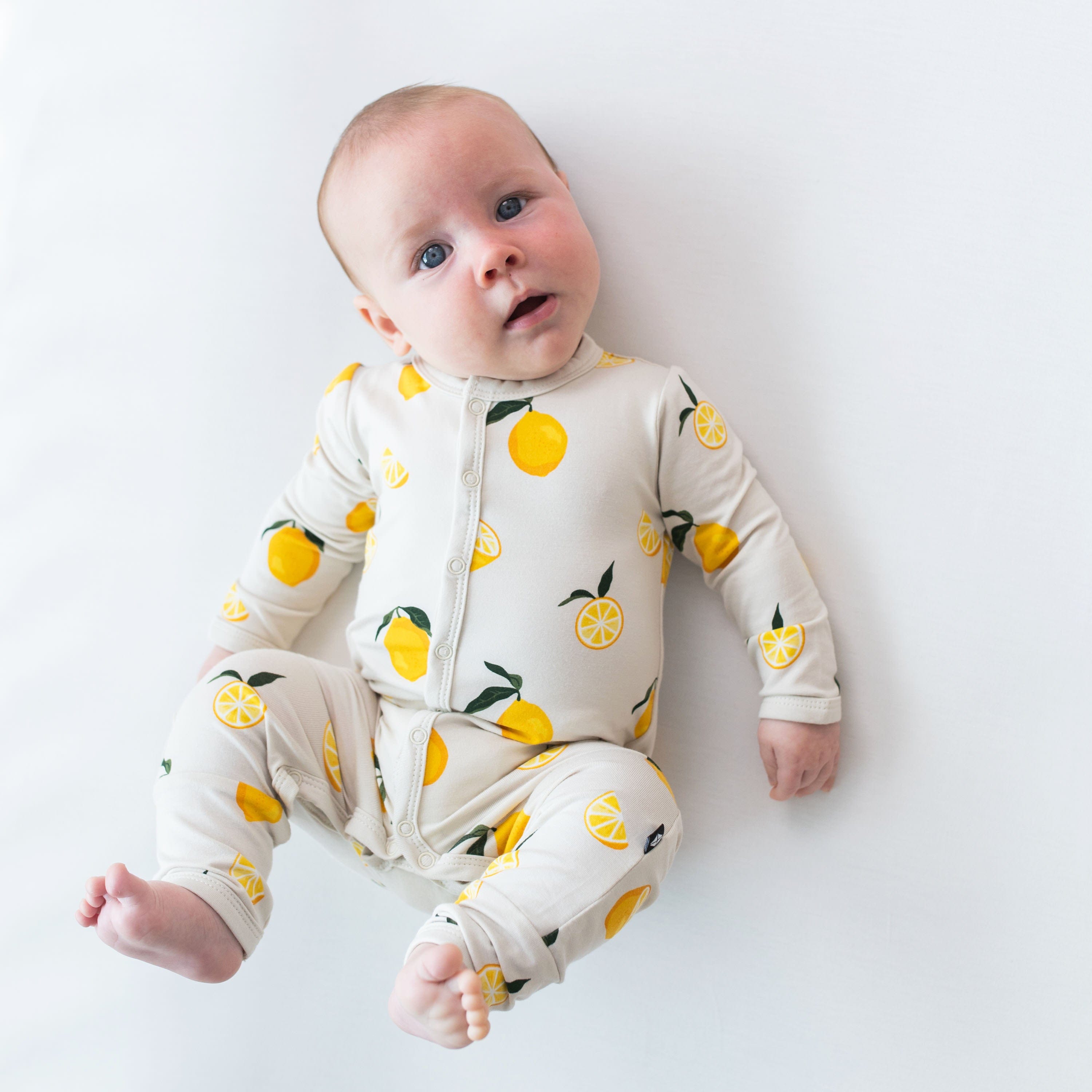 Infant wearing Kyte Baby Romper in Lemon