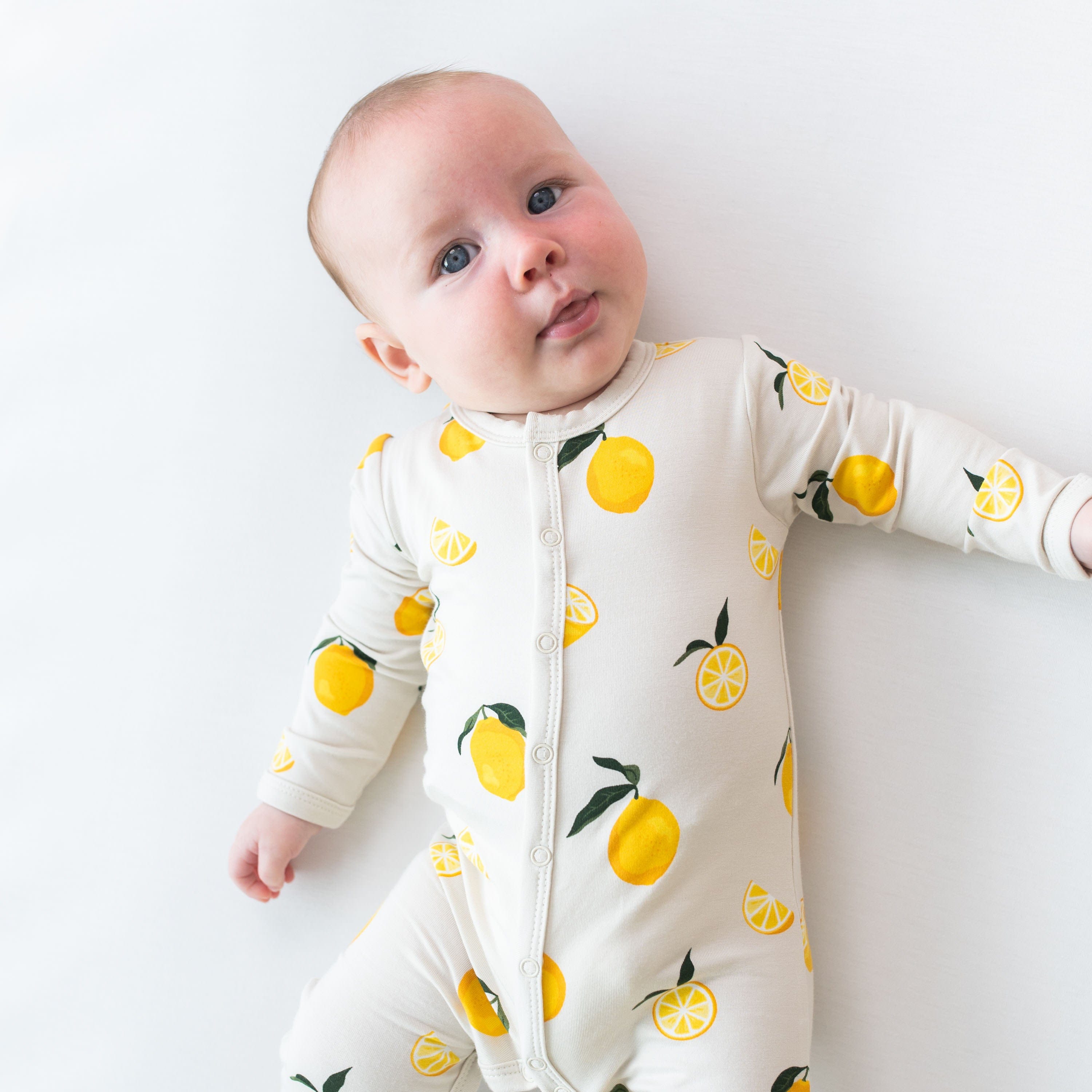 Child wearing long sleeve Kyte Baby Romper with snaps in Lemon