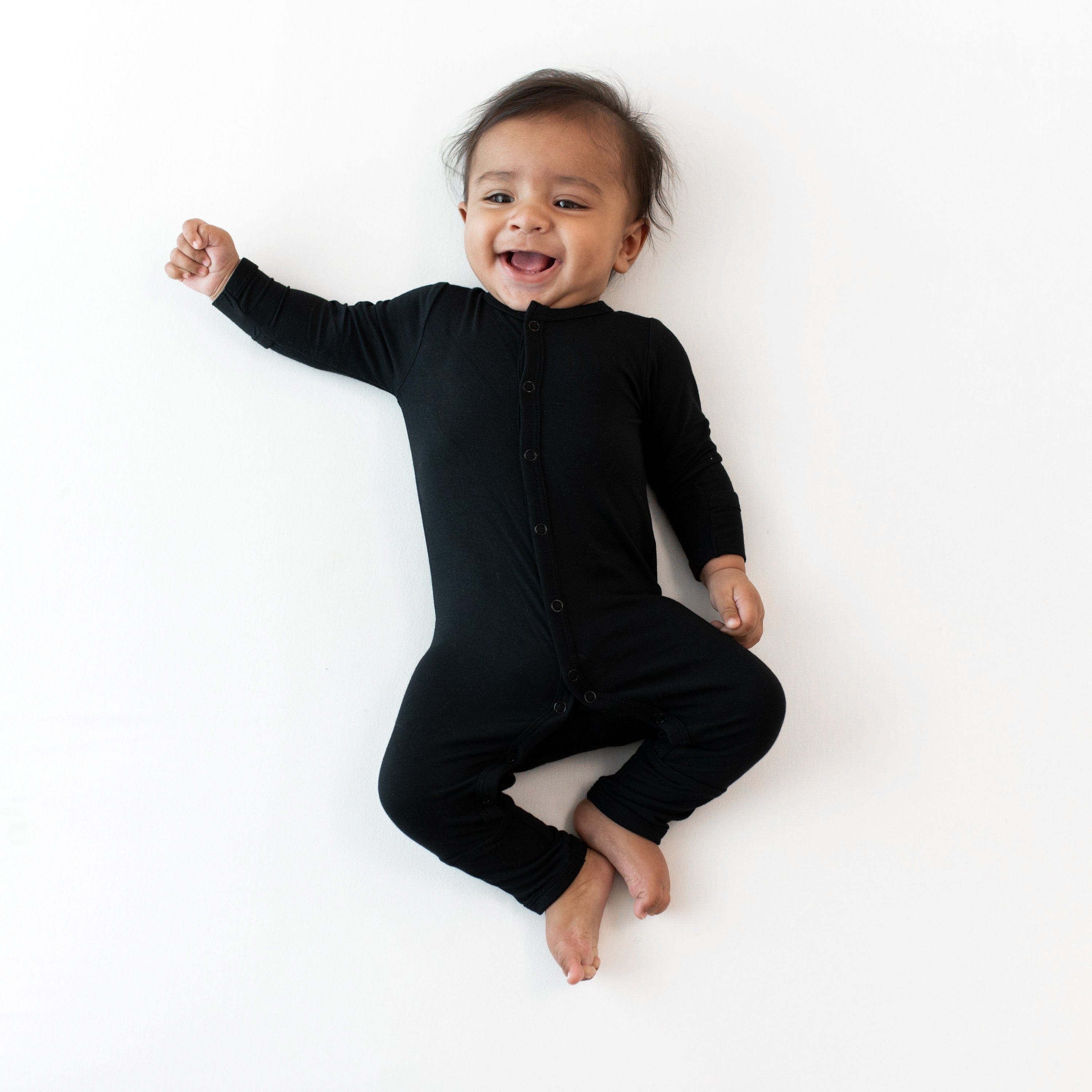 Smiling infant wearing Kyte Baby Romper in Midnight
