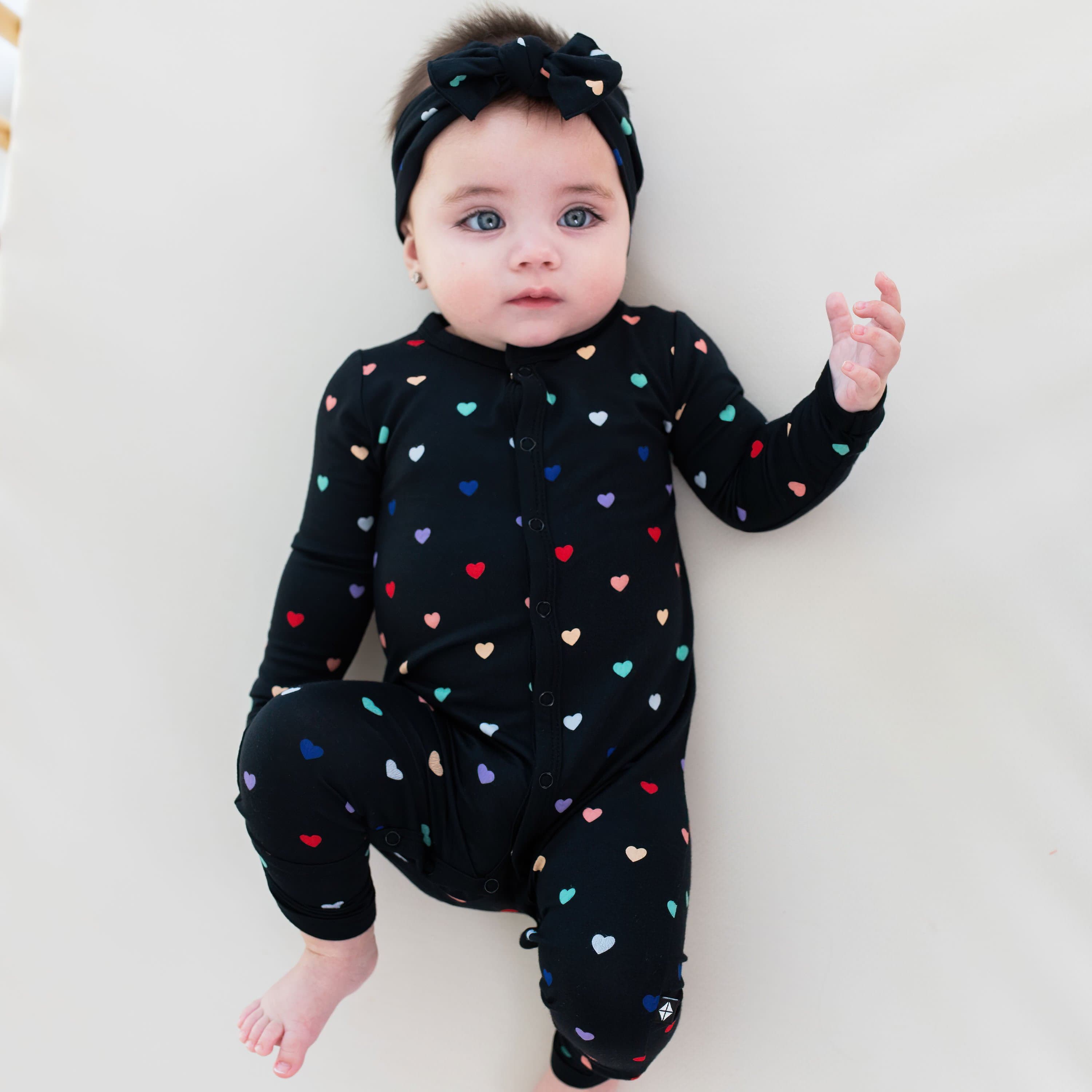 Infant wearing Kyte Baby Romper in Midnight Rainbow Heart