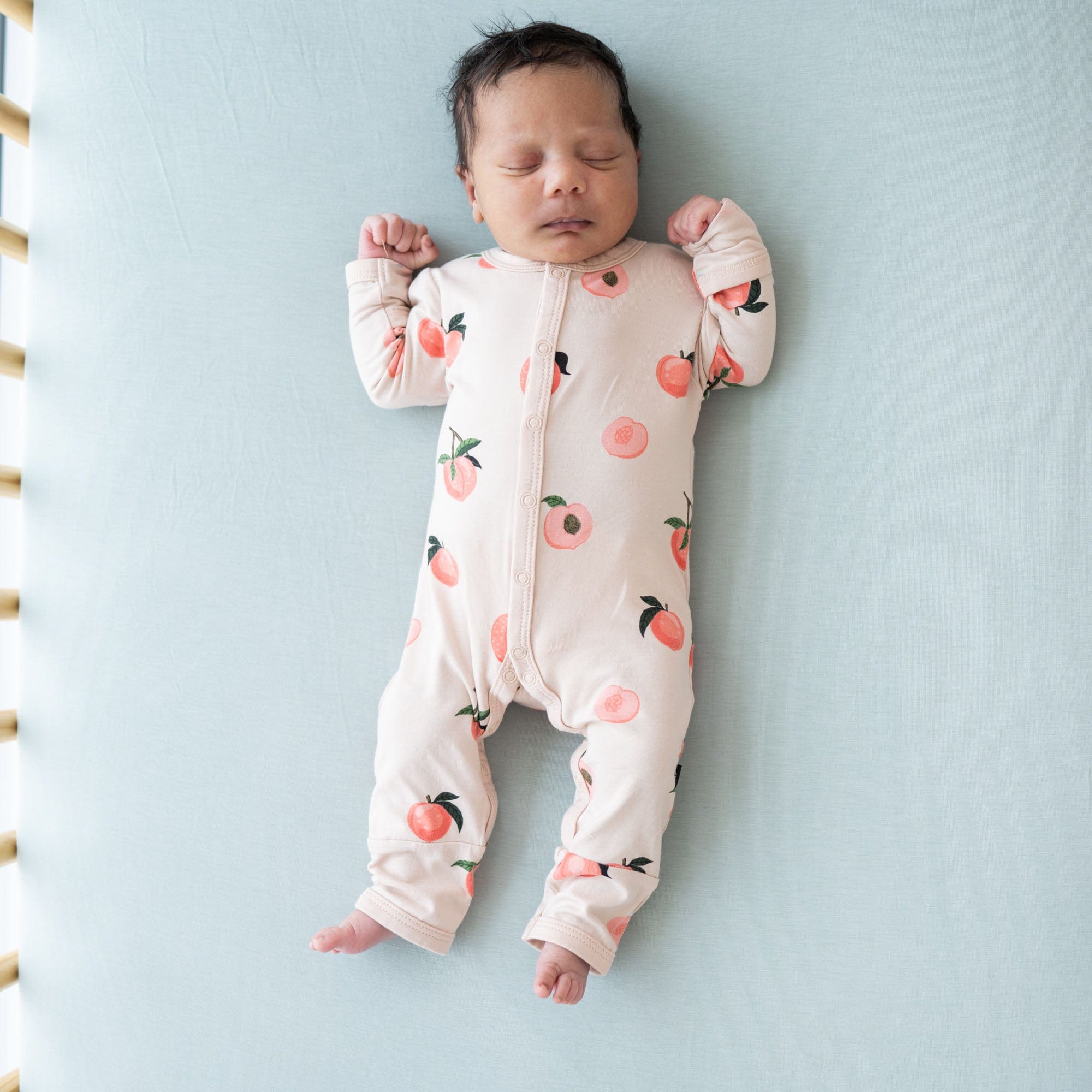 Infant wearing Kyte Baby Romper pajamas in Peach
