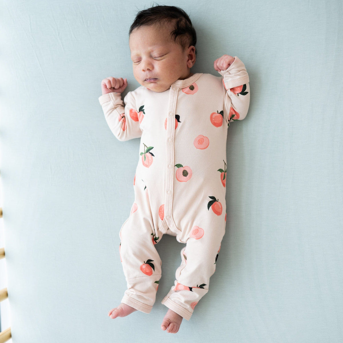 Newborn sleeping in Kyte Baby Romper in Peach