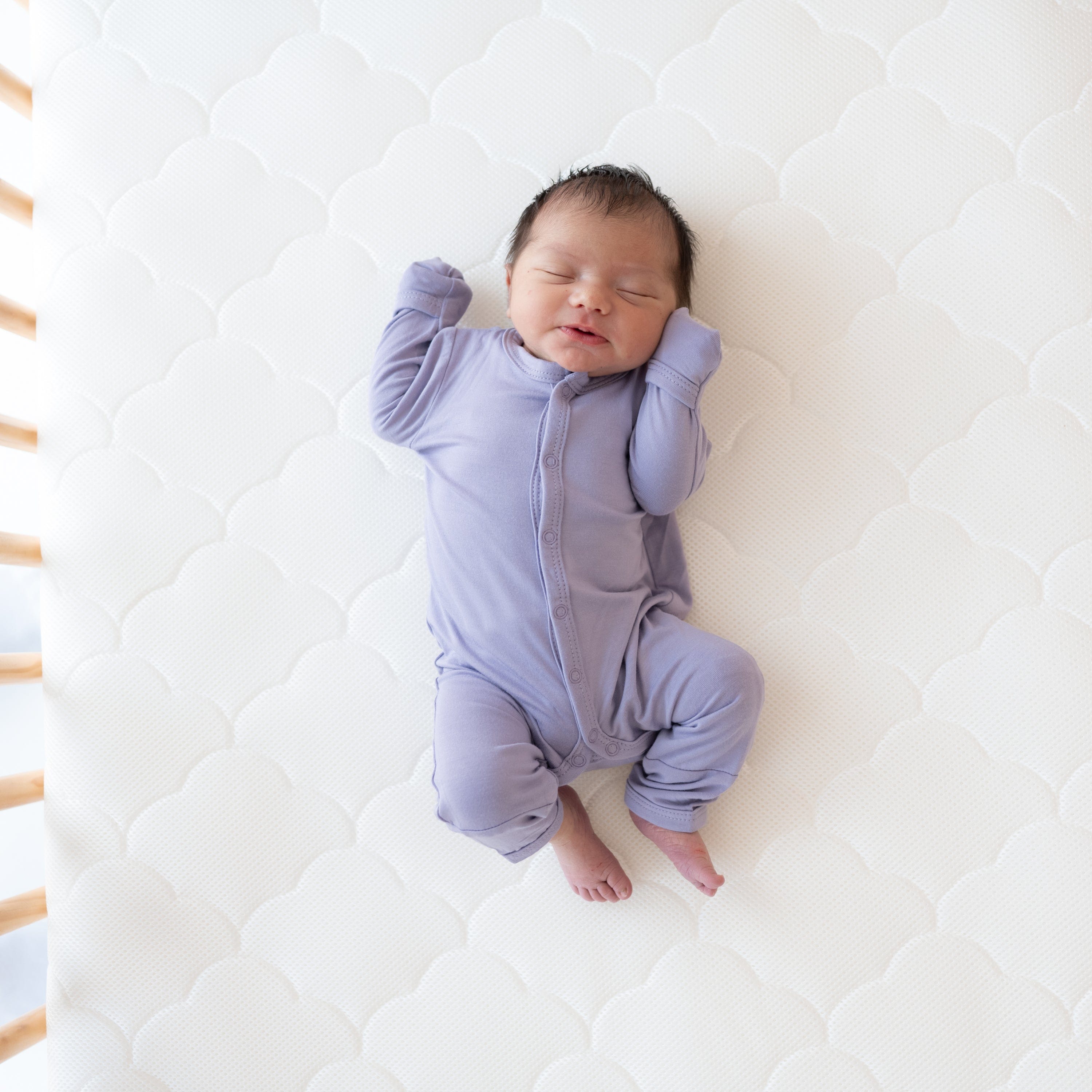 Newborn wearing long sleeve Kyte Baby Romper with snaps in Taro