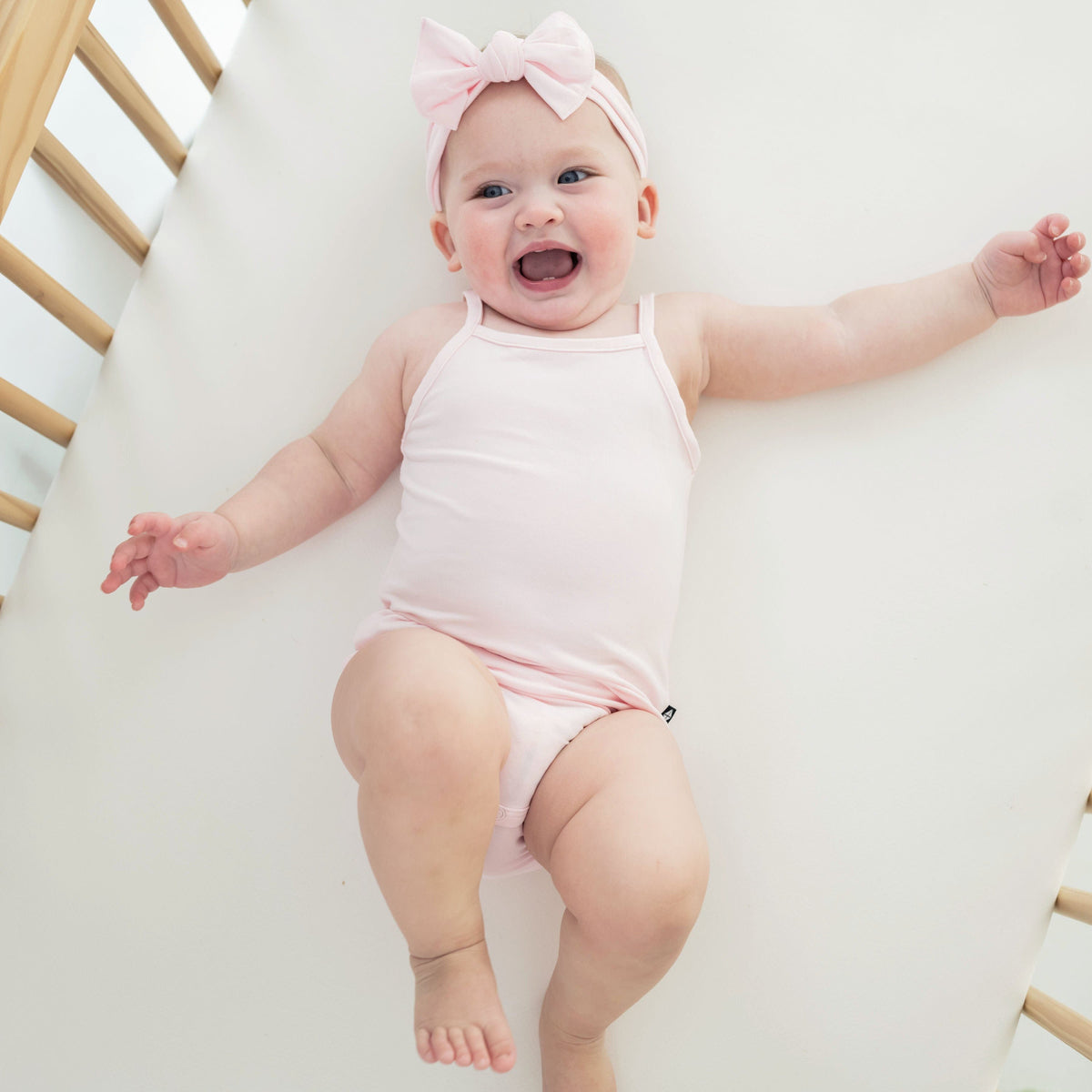 Infant wearing Kyte Baby Spaghetti Strap Leotard in Sakura pink