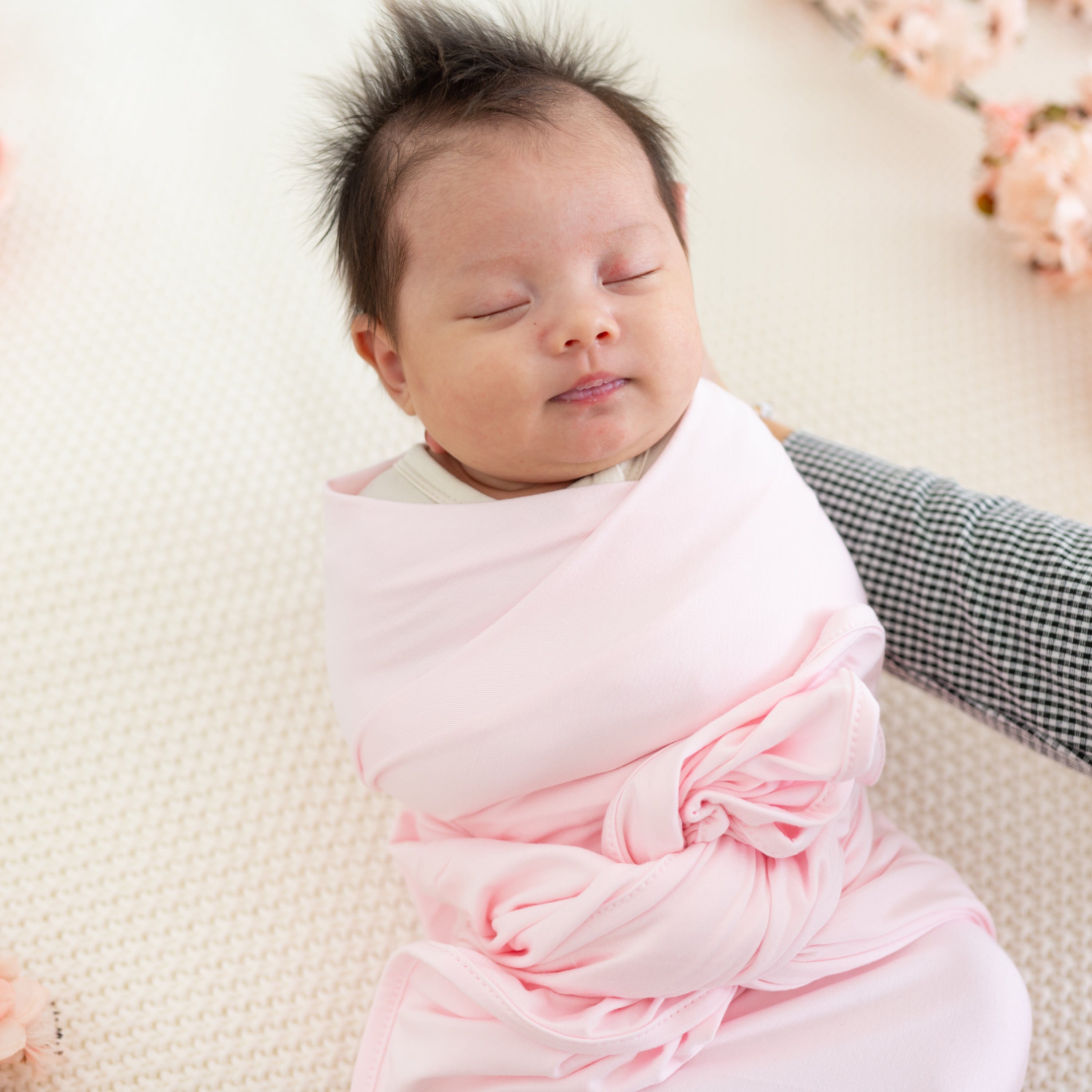 Newborn swaddled in Kyte Baby Swaddle Blanket in Sakura