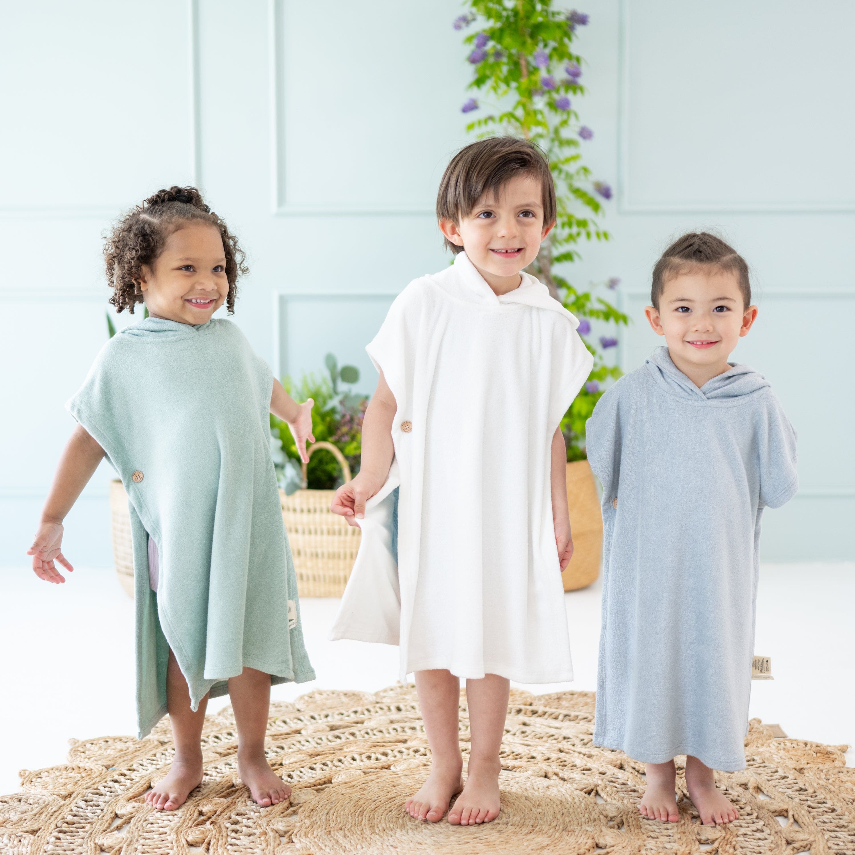 Toddlers wearing bamboo hooded Kyte Baby Swim in Sage, Cloud and Fog