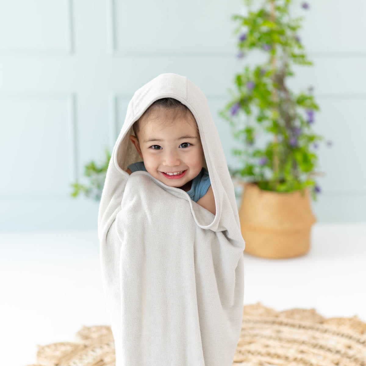 Toddler wrapped in Kyte Baby Hooded Bath Towel in Oat