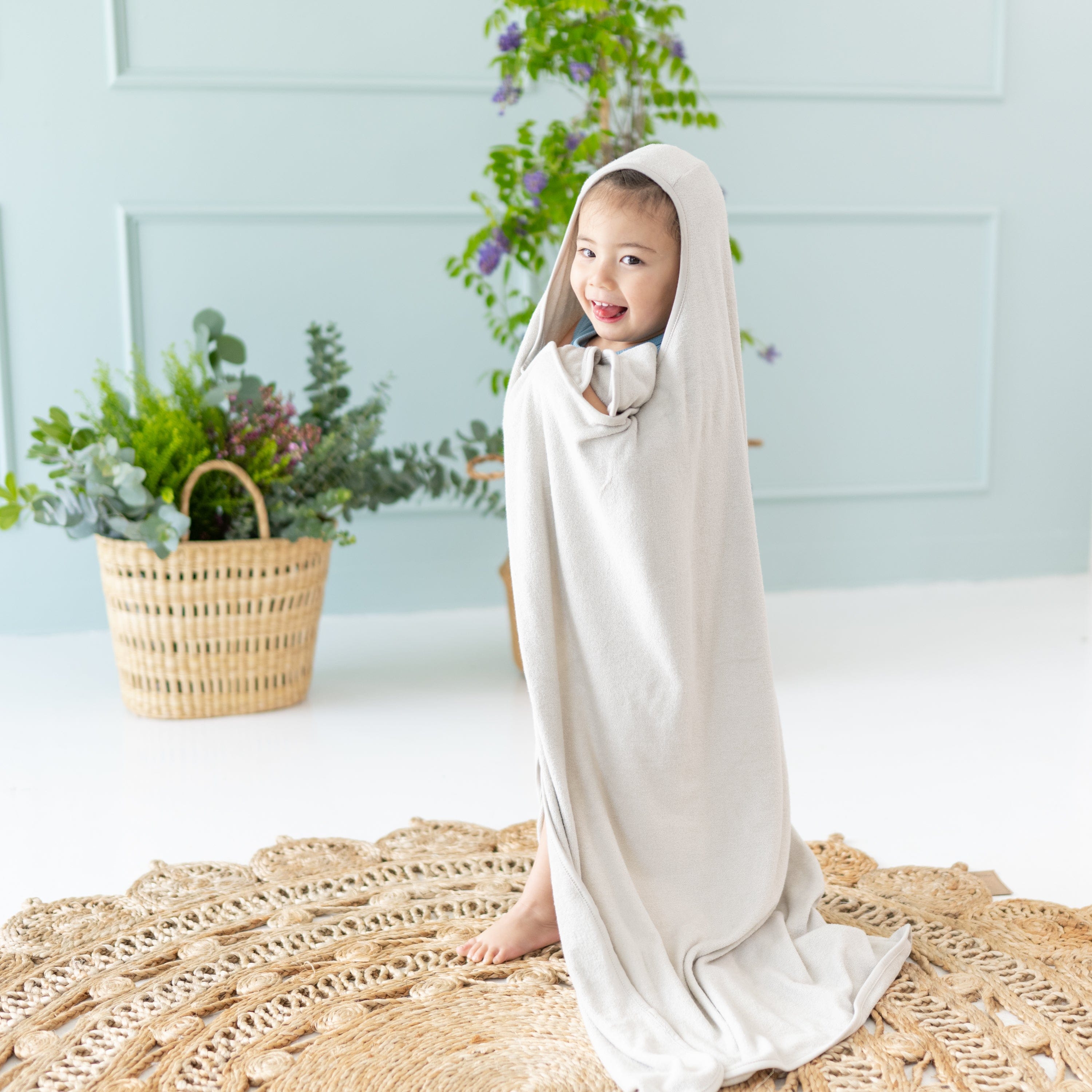Child holding Kyte Baby Toddler Hooded bamboo terry Bath Towel in Oat