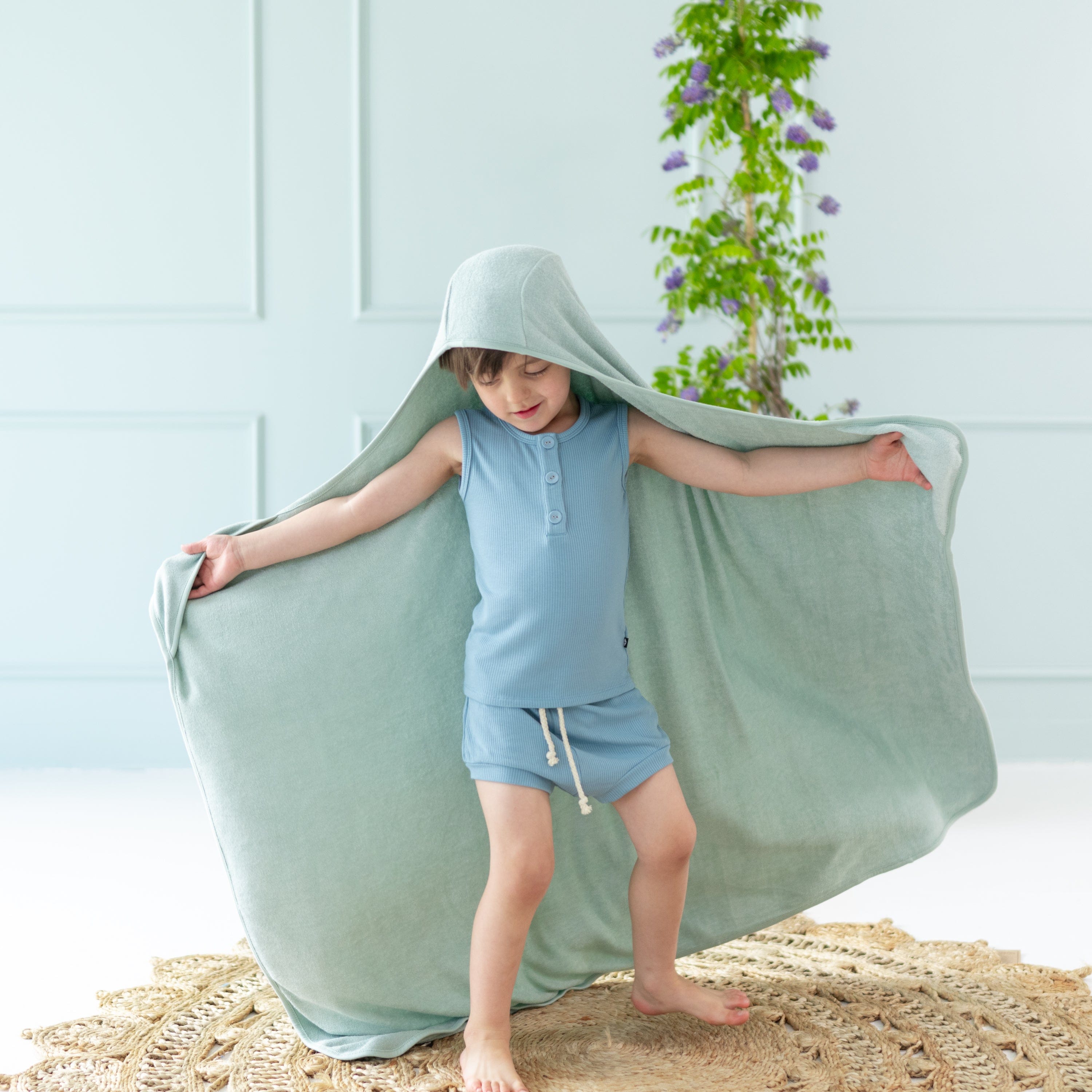 Child wrapped in Kyte Baby Toddler Hooded Bath Towel in Sage green